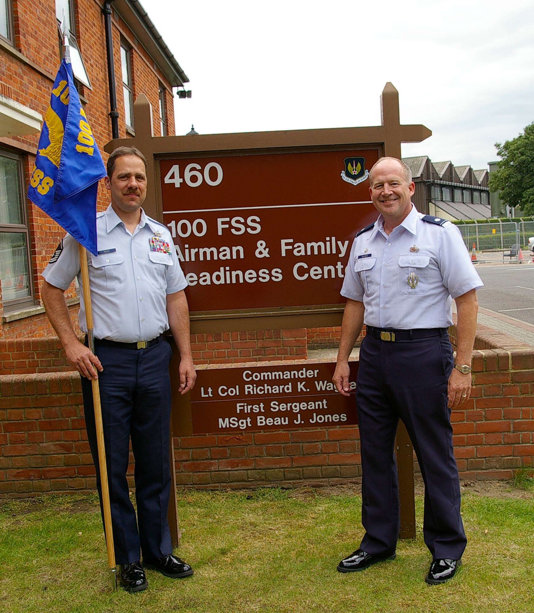 Lt. Col. Richard Wagner, right, the first commander of the newly-designated 100th Force Support Squadron, stands beside the newly unveiled sign in front of Building 460, June 13. Master Sgt. Thomas Green, the acting first sergeant, holds the unit's guidon. The unit was formed as part of an ongoing Air Force-wide merger of mission support and services squadrons. (U.S. Air Force photo by Karen Abeyasekere)