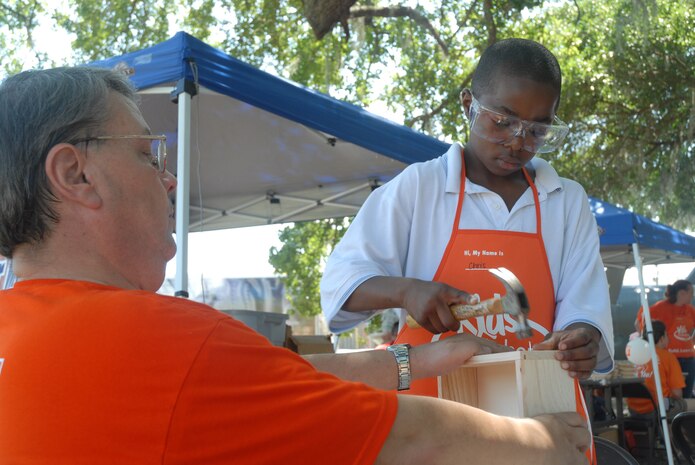Chris Brown, 11, builds a box with the help of Mike Brown at the Home Depot workshop at the base picnic June 7. Chris is the son of Tech. Sgt. Africo Smalls, 315th Maintenance Squadron. (U.S. Air Force photo/Senior Airman Sam Hymas)