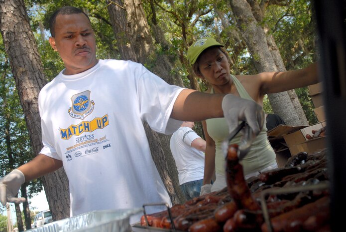 Senior Airman Mark Roper and Alma Whittemore, grill sausages at the picnic grounds for the MatchUP base picnic June 7. The picnic was the kickoff event for Air Mobility Command's summer program where players can win prizes by participating in base activities. Airman Roper is a reservist assigned to the 38th Aerial Port Squadron and Ms. Whittemore is a food and beverage manager with the 437th Force Support Squadron. (U.S. Air Force photo/Senior Airman Sam Hymas)
