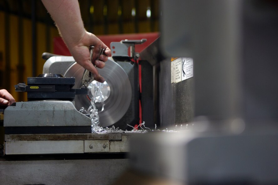 BALAD AIR BASE, Iraq -- An Airman, assigned to the 332nd Expeditionary Aircraft Maintenance Squadron Fabrication Flight fashions a piece of metal into an aircraft component using a computer numerical controlled lathe here, June 10. The CNC lathe allows the Airmen to enter and store codes into the machine that tells it the dimensions the component should be. The Fabrication Flight Airmen fix and build aircraft components needed to fly F-16s, C-130s, unmanned aerial vehicles, helicopters and Army assets. The Airmen complete approximately 1,400 jobs monthly. (U.S. Air Force photo /Staff Sgt. John Ayre)