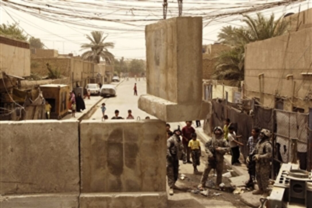 U.S. Soldiers guide a barrier down while a crane lowers it to a street opening near the Joint Security Station in Shula, Iraq, June 8, 2008. 