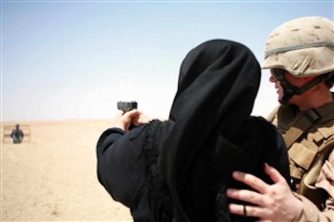 U.S. Marine 1st Lt. Kathryne B. Schilling coaches a woman as she prepares to shoot a pistol during her training to become a Sister of Ferris, June 4, 2008, Ferris, Iraq. The Sisters of Ferris will inspect women for weapons, suicide vests, large amounts of cash and contraband at entry control points. Schilling is assigned to Combat Logistics Battalion 1, 1st Marine Logistics Group.
