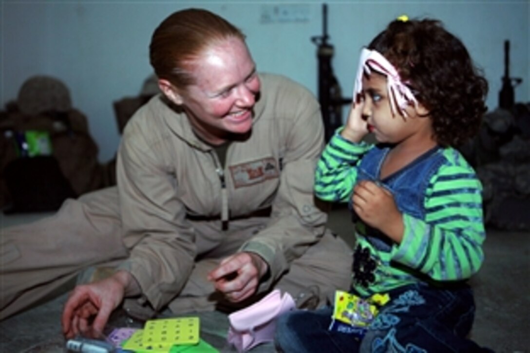 U.S. Marine Corps Cpl. Rebekah D. Hall entertains an Iraqi girl as the child’s mother reviews search procedures as part of "Sisters of Ferris" training in Ferris, Iraq, June 5, 2008. The Sisters of Ferris will inspect women for weapons, suicide vests, large amounts of cash and contraband at entry control points. Hall is assigned to Combat Logistics Battalion 1, 1st Marine Logistics Group.
