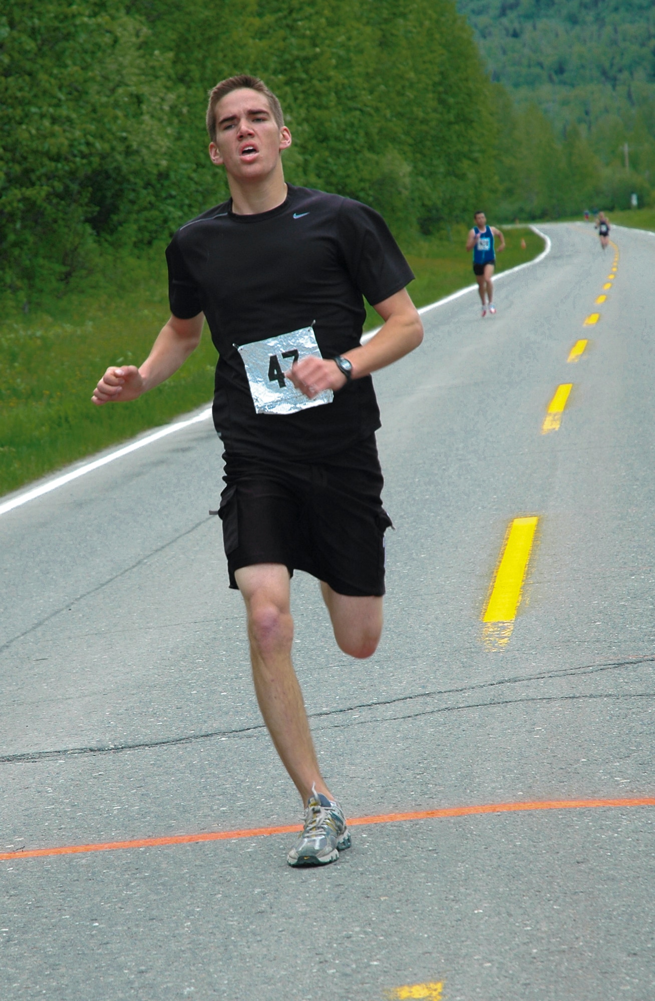 Anchorage, Alaska -- Fifteen-year-old Air Force family member Alex Babos of Eagle River crosses the finish line of the five-mile portion of the 34th annual Arctic Valley Run Saturday with a time of 31 minutes, 55.53 seconds, just seconds before Army Ten-Miler qualifier winner Roland Delavega, Headquarters and Headquarters Company, 725th Brigade Support Battalion. (U.S. Army photo by Mary M. Rall)