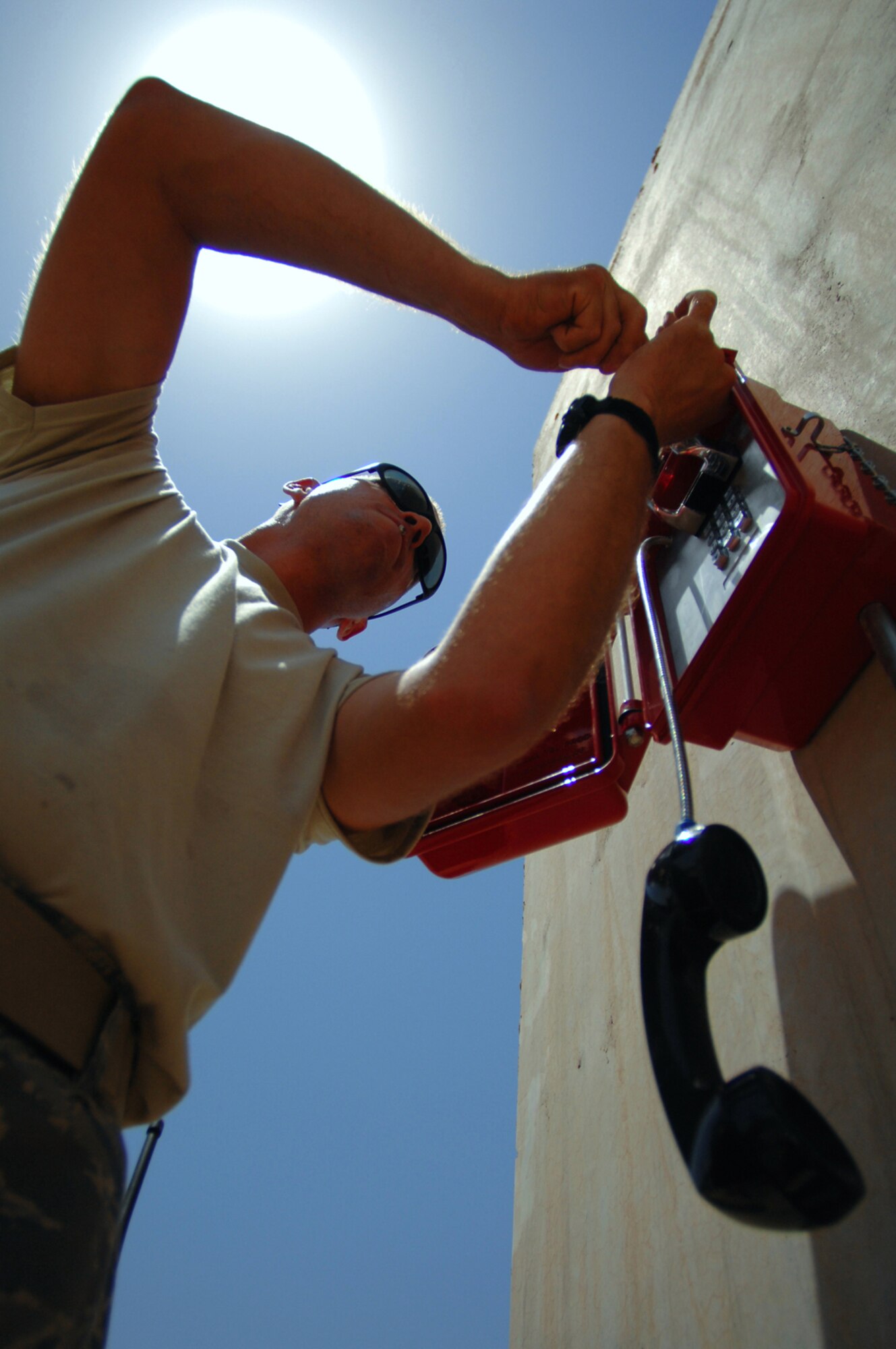 BALAD AIR BASE, Iraq -- Staff Sgt. Phillip Balson, 332nd Expeditionary Communications Squadron infrastructure technician, mounts a new, durable, weather- resistant emergency phone on a T-barrier in the Air Force personnel housing area here, June 13. More than 120 lines were installed throughout the area to allow servicemembers to give notice of their whereabouts during accountability checks. Sergeant Balson is deployed from Tinker Air Force Base, Okla. (U.S. Air Force photo/ Senior Airman Julianne Showalter)