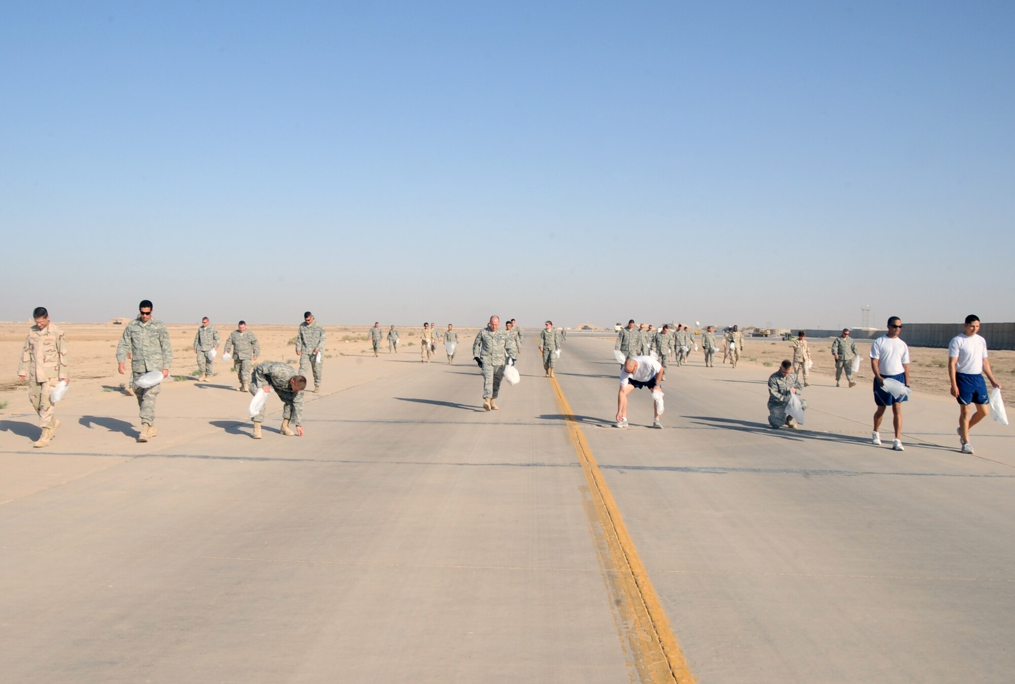 ALI BASE, Iraq -- Airmen of the 407th Air Expeditionary Group, sweep approximately one mile of the flightline for foreign object debris that could damage aircraft engines or maintenance equipment here June 14. The group performs FOD walks frequently to maintain a clean and safe flightline for the passage of aircraft in and out of the installation. (U.S. Air Force photo/Tech. Sgt. Sabrina Johnson)
