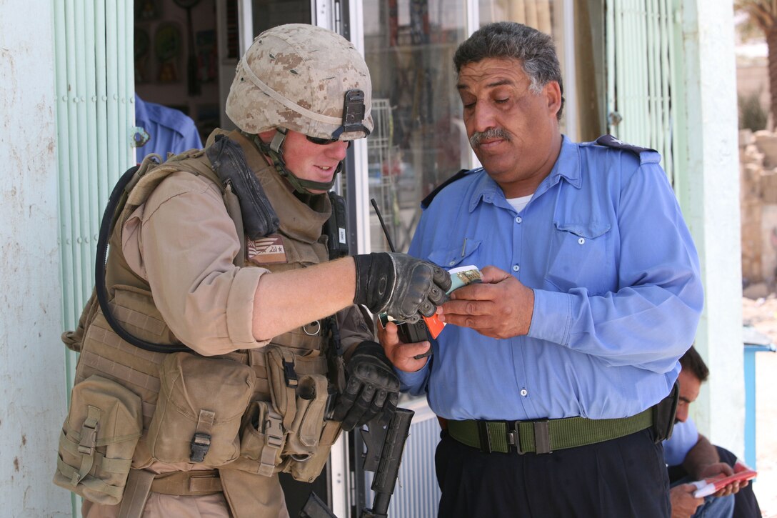 Corporal Clifford Sandy, a vehicle operator with Police Transition Team 23, has a conversation with an Iraqi policeman at a local police station with the help of an Arabic-to-English dictionary. Before deploying, the team learned about Iraqi customs and was taught a limited amount of Arabic through pre-deployment training.