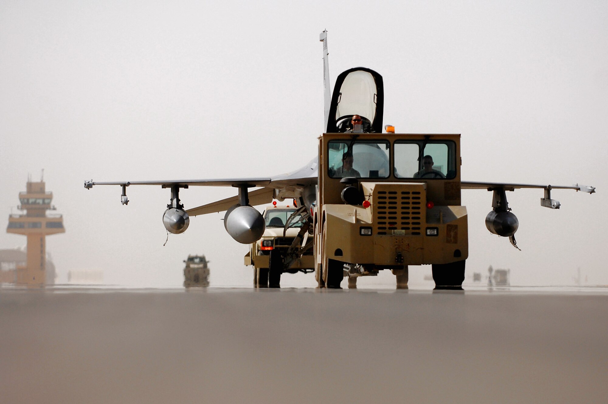 Members of the Iowa and the Wisconsin Air National Guard, assigned to the 332nd Expeditionary Aircraft Maintenance Squadron at Balad Air Base, Iraq, tow an F-16 Fighting Falcon to a hardened aircraft shelter June 13. Aircraft and personnel from Iowa and Wisconsin Air National Guard units will return to the U.S., after being in Iraq for four months.  F-16s and Airmen from South Dakota and New York ANG units have arrived at Balad to take their places. Rotating fighters helps reduce the amount of time the aircraft are exposed to the hot and dusty weather of Iraq, which can wreak havoc on the planes' components. (U.S. Air Force photo/Senior Airman Julianne Showalter)