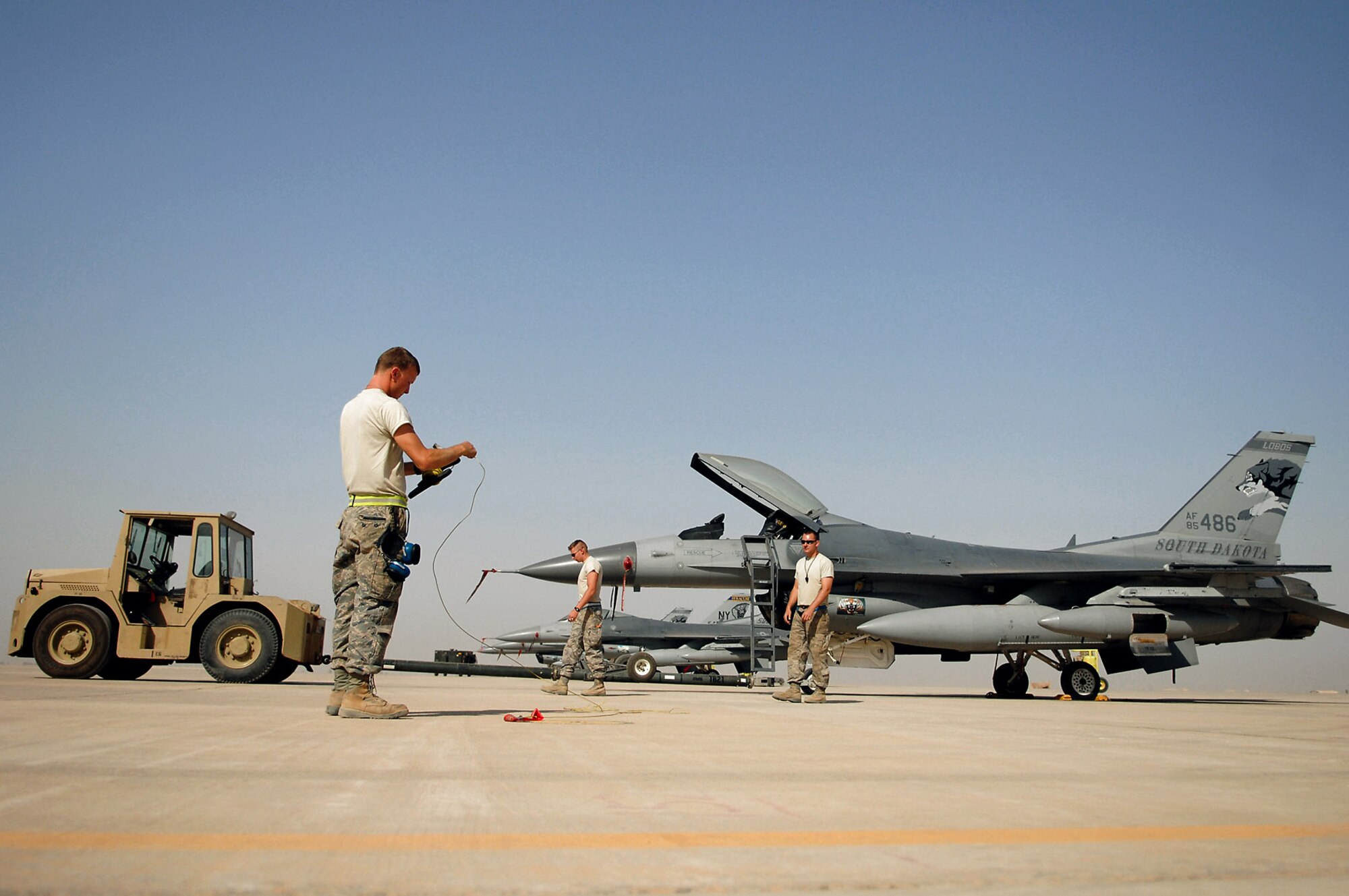 Tech. Sgt. Jake Hermanson(left) rolls up an F-16 Fighting Falcon grounding cable June 13 before towing the jet to a hardened aircraft shelter during a transition between fighter squadrons at Balad Air Base, Iraq.  Aircraft and personnel from Iowa and Wisconsin Air National Guard units will return to the U.S. after being in Iraq for four months.  F-16s and Airmen from South Dakota and New York ANG units have arrived here to take their places.  Rotating fighters helps reduce the amount of time the aircraft are exposed to the hot and dusty weather of Iraq, which can wreak havoc on the planes' components.  Sergeant Hermanson, assigned as a 332nd Expeditionary Aircraft Maintenance Squadron crew chief, is deployed from the Iowa Air Guard.  (U.S. Air Force photo/Senior Airman Julianne Showalter) 