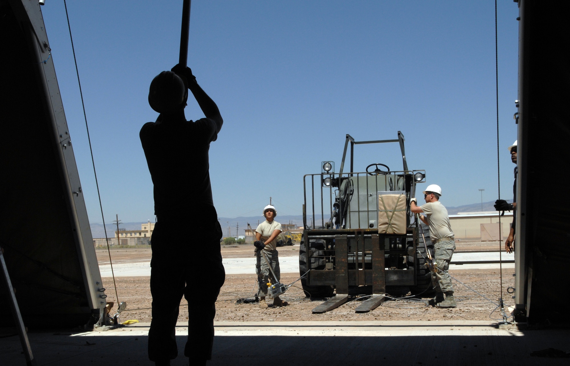 Airman 1st Class Karla Jiminez and Staff Sgt. Shawn Cullen, both from the 49th Civil Engineer Squadron, use a Tirfor and cable assemblies to pull fabric into position on a BEAR Base dome shelter as a part of the Structural Contingency Course at Holloman Air Force Base, N.M. June 3. Meanwhile, another student uses a Purlin installation tube to guide the fabric over the roof frame of the shelter and ensure it does not get caught. (U.S. Air Force photo/Airman Sondra M. Wieseler)