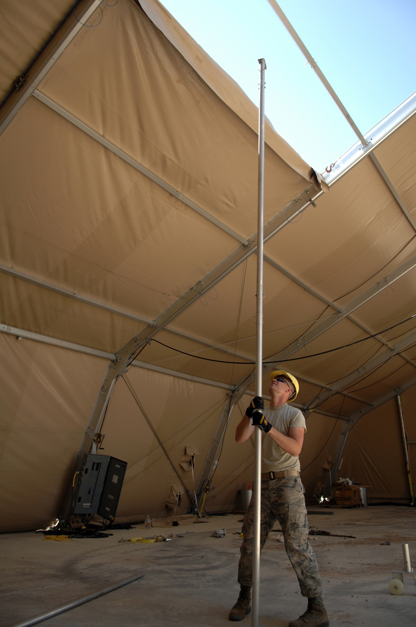 Airman 1st Class Jeremiah Perish from the 49th Civil Engineer Squadron, a student in the new Structural Contingency Course, uses a Purlin installation tube to help pull fabric over the roof frame of the BEAR Base dome shelter June 3 at Holloman Air Force Base, N.M. The fabric has a weather flap on its end which hangs free and can get caught as its being pulled into position. The tube is used to bump the fabric as it?s pulled so it doesn?t get caught. (U.S. Air Force photo/Airman Sondra M. Wieseler)