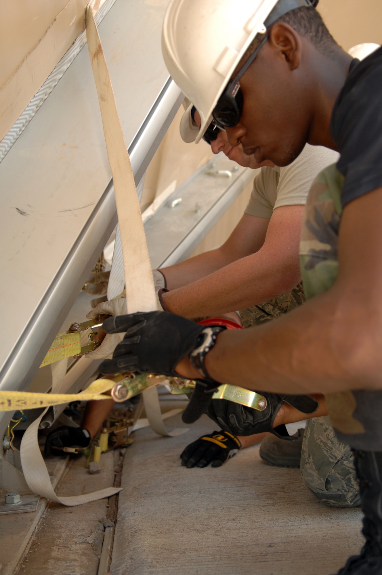 Airman 1st Class Chauncy Williams, 49th Material Maintenance Squadron, and Staff Sgt. Shawn Cullen, 49th Civil Engineer Squadron, attach door fabric tensioning straps to their ratchets in the setting up of a BEAR Base dome shelter June 3 at Holloman Air Force Base, N.M. The students set up the shelter as a part of the Structural Contingency Course lesson plan. They tore down the shelter earlier and returned it to operational status the same day. (U.S. Air Force photo/Airman Sondra M. Wieseler)