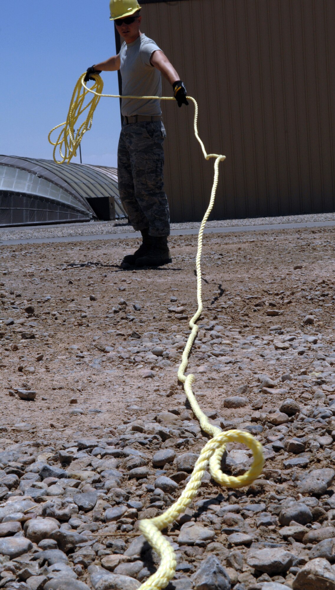 Airman 1st Class Jeremiah Perish from the 49th Civil Engineer Squadron, a student in the new Structural Contingency Course, is preparing a throw-over rope before attaching it to a fabric pull-over cable in the setting up of a BEAR Base dome shelter June 3 at Holloman Air Force Base, N.M. The students in the course tore down the shelter earlier and returned it to operational status the same day. (U.S. Air Force photo/Airman Sondra M. Wieseler)