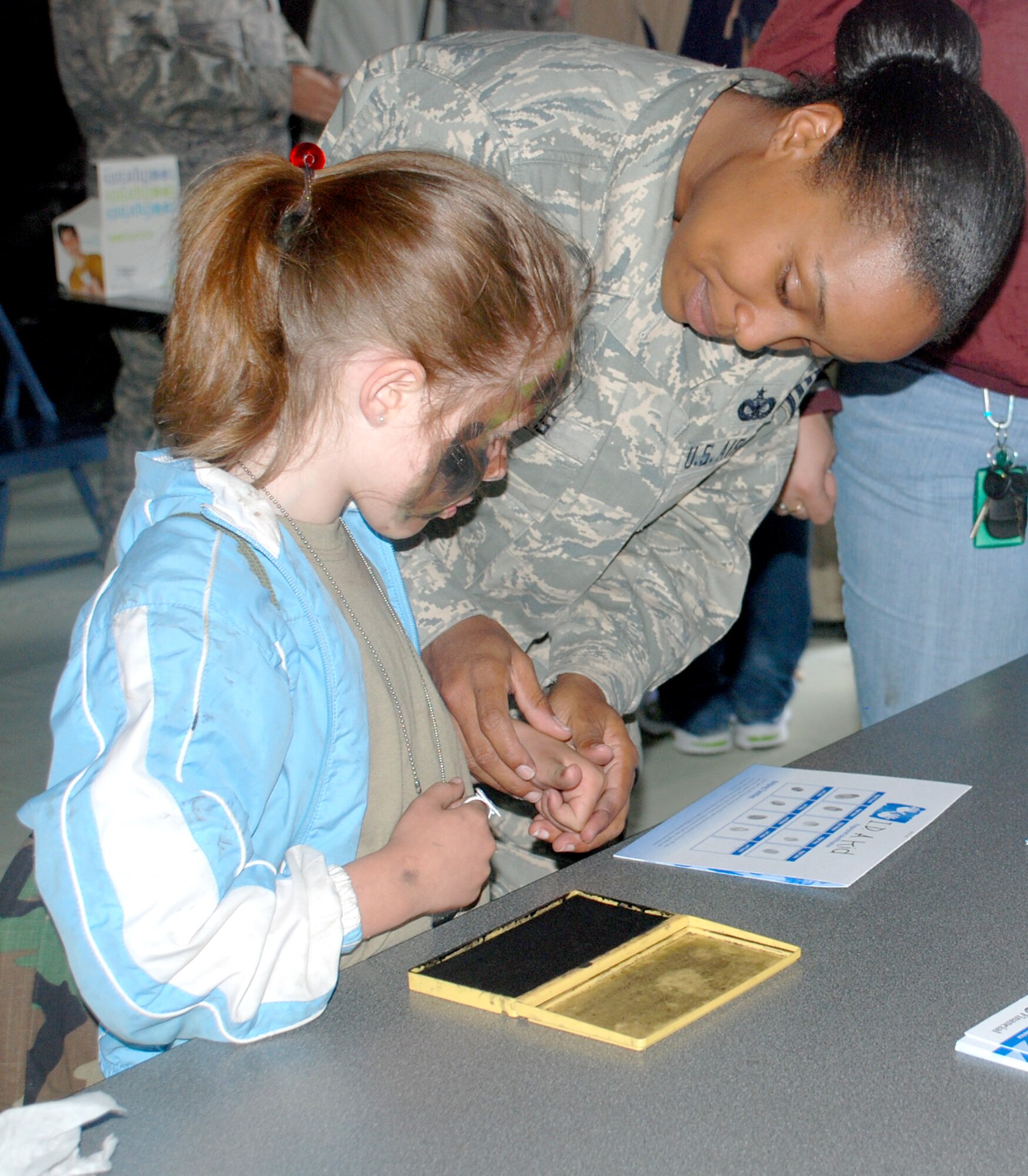 Staff Sgt. Tambria Owens, 90th Security Forces Squadron, helps a Jr. Deployer participant stamp her fingerprints for identification in Fewastan.