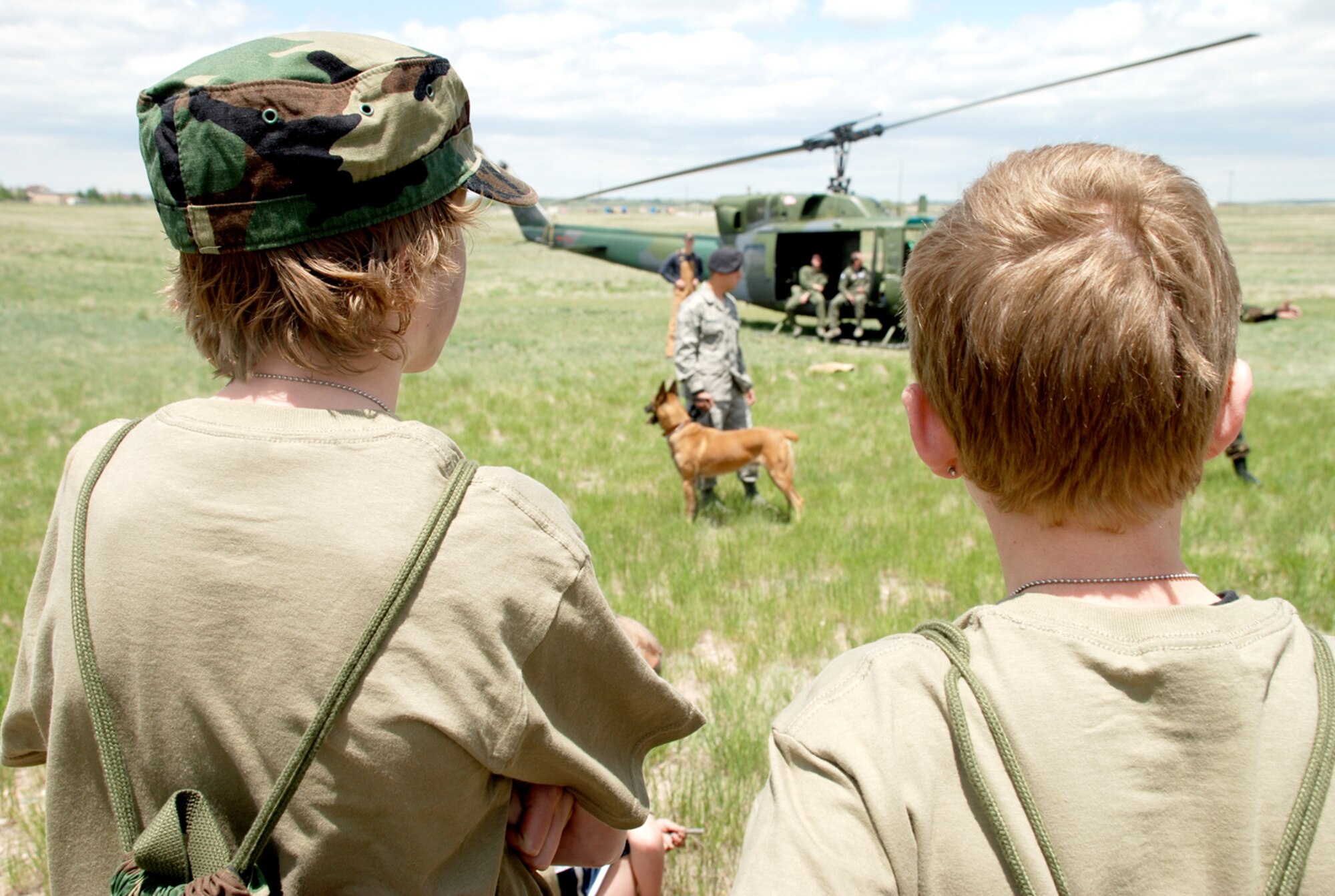 Two Jr. Deployer participants watch as Senior Airman Daren Marshall, 90th Security Forces Squadron, demonstrates K-9 discipline procedures during the Special Processing, Authorization and Combat Effectiveness (S.P.A.C.E) Jr. Deployer Saturday. The event allowed children to get a taste of the deployment process as experienced by their parents.