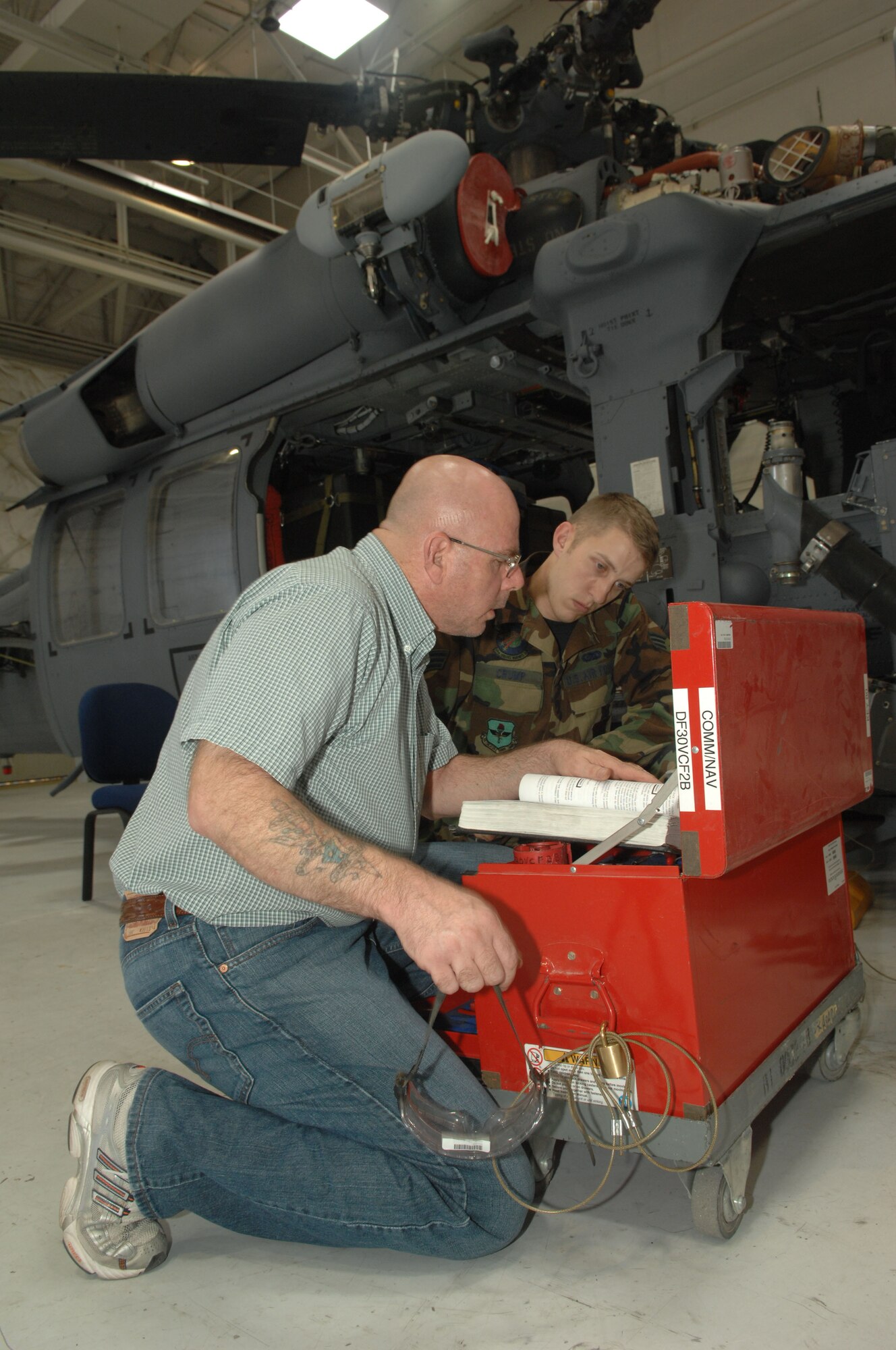 Mr. Marvin Voorhees III, Communications and Navigations Non-Commissioned Officer in Charge Air Reserve Technician, instructs Senior Airman Jeffery Crump, an Electronic Warfare Apprentice, on the initial procedures of replacing an HH-60s rescue hoist. Mr. Voorhees has been with the unit since 1990, holds the rank of Master Sgt. when in military status, and has participated in 6 large scale operations from DESERT SHIELD/STORM to ENDURING FREEDOM.  (U.S. Air Force photo by Senior Airman Alesia Goosic) 

