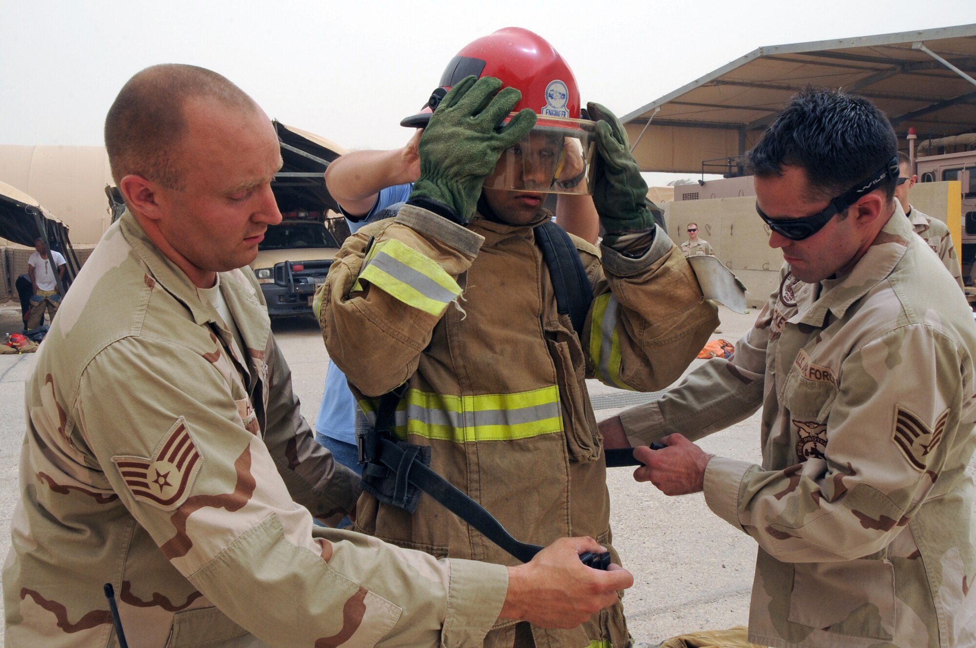 ALI BASE, Iraq -- Staff Sgt. Scott Herbert and Staff Sgt. Aaron Brackett, 407th Expeditionary Civil Engineer Squadron firefighters, assist an Iraqi firefighter don his fire gear during the "firefighter challenge" here June 16. The Air Force firefighters provide reoccurring training to local Iraqi firefighters helping them better serve their communities. The Iraqis had to pass the challenge in under eight minutes to graduate the Basic Firefighter Skills Course, the firefighters had to complete seven tasks during the challenge. Sergeant Herbert is deployed from Ellsworth AFB, S.D. and Sergeant Brackett is deployed from Elmendorf AFB, Alaska. (U.S. Air Force photo/Tech. Sgt. Sabrina Johnson)
