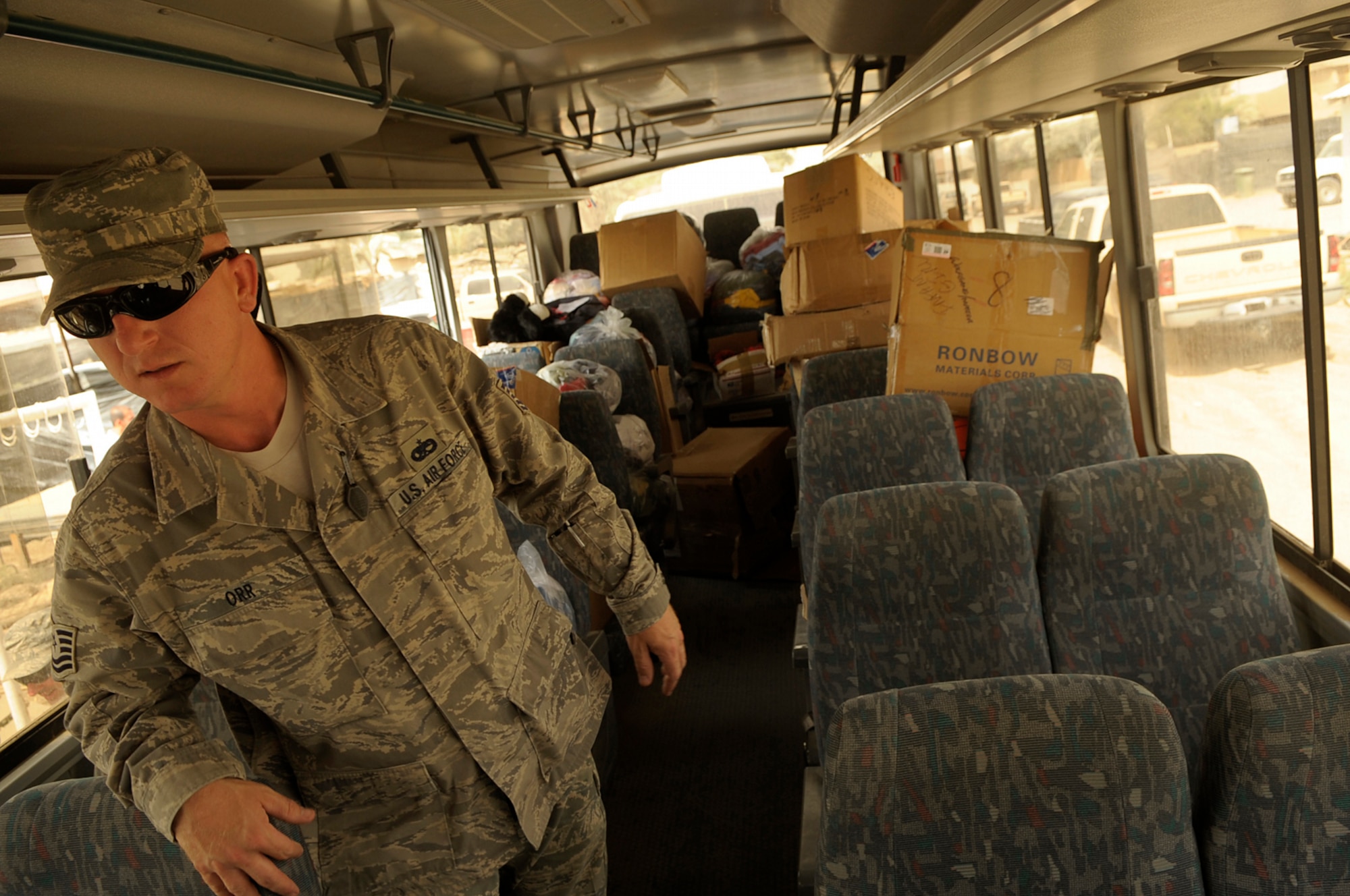 SATHER AIR BASE, Iraq -- Tech. Sgt. John Orr from the 447th Expeditionary Logistics Readiness Squadron walks down the aisle of a bus loaded with toys and other gifts for local Iraqi children donated by Airmen here June 6. (U.S. Air Force photo/Tech. Sgt. Jeffrey Allen)