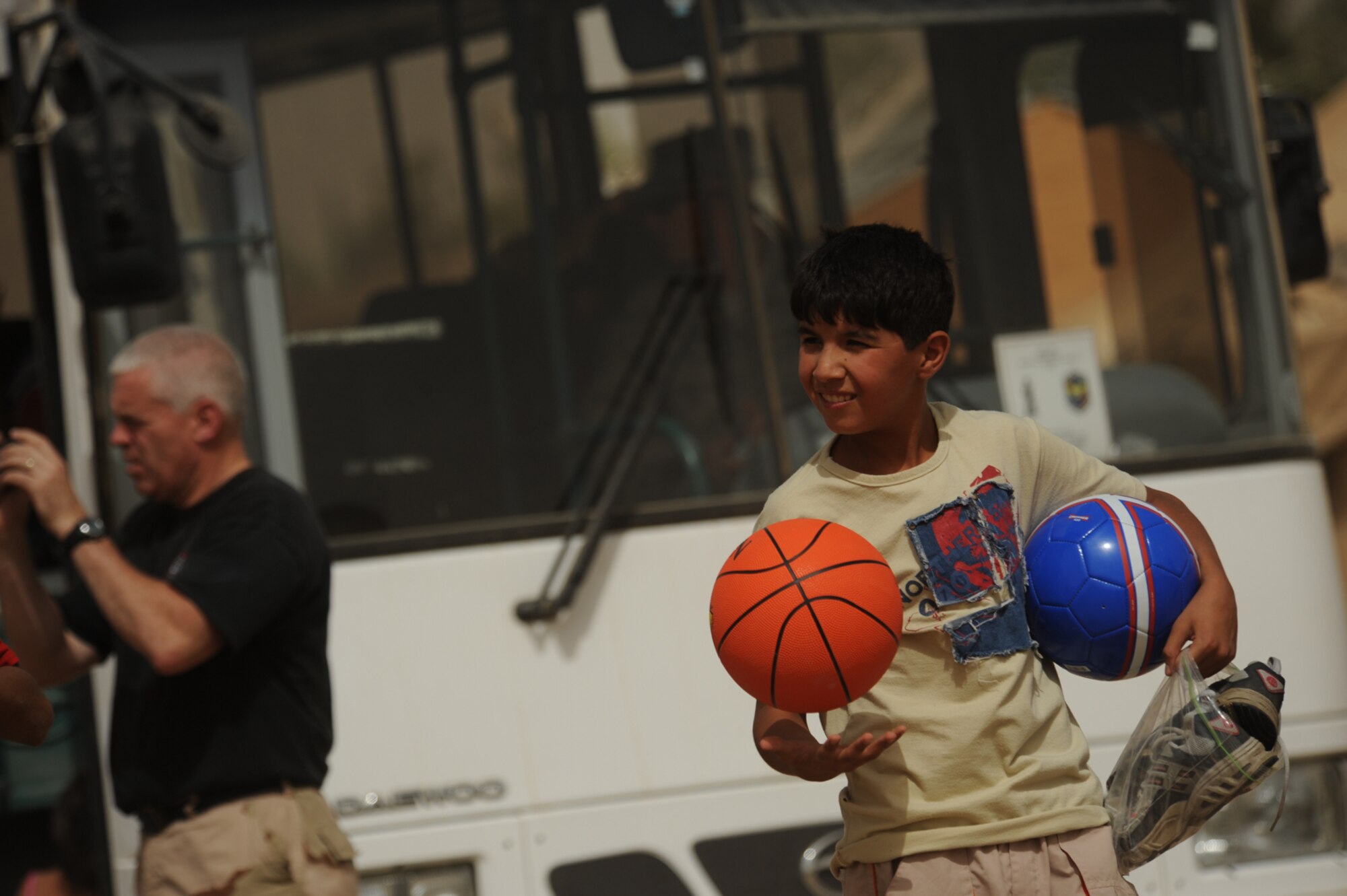 SATHER AIR BASE, Iraq -- A young Iraqi boy carrires a basketball and soccer ball that were donated by Airmen here June 6. The gifts were donated and delivered as part of the Good Neighbor Program at Sather AB. (U.S. Air Force photo/Tech. Sgt. Jeffrey Allen)