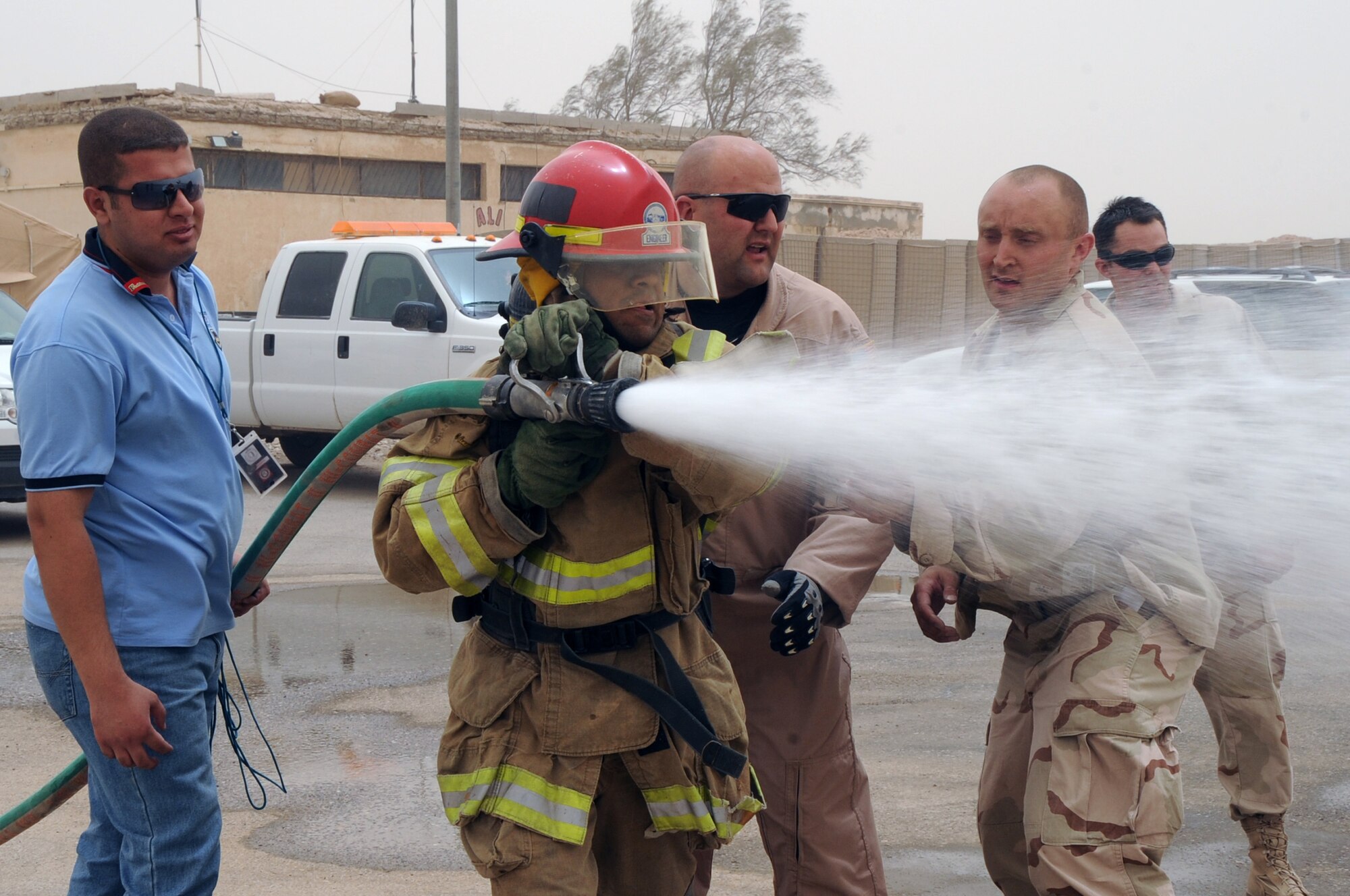 ALI BASE, Iraq -- Tech. Sgt. Chris Kammermeier and Staff Sgt. Scott Herbert, 407th Expeditionary Civil Engineer Squadron firefighters, watch an Iraqi firefighter compete in the "firefighter challenge" here June 16. The Air Force firefighters provide reoccurring training to local Iraqi firefighters helping them better serve their communities. The Iraqis had to pass the challenge in under eight minutes to graduate the Basic Firefighter Skills Course, the firefighter had to drag the hose 150 feet before knocking over a cone with the water. Sergeant Kammermeier is deployed from McGuire AFB, N.J. and Sergeant Herbert is deployed from Ellsworth AFB, S.D. (U.S. Air Force photo/Tech. Sgt. Sabrina Johnson)