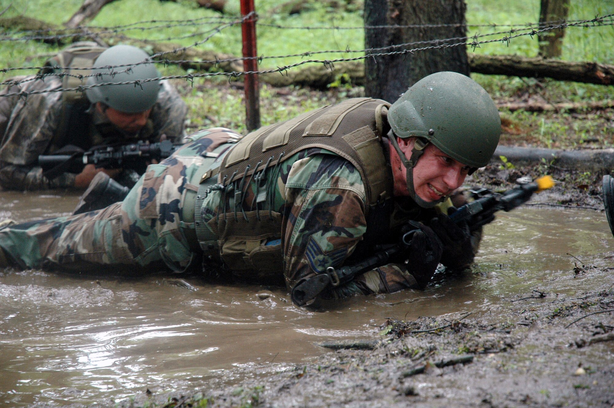 Students in the Air Force Phoenix Warrior Training Course 08-5 crawl under barbed wire and through water during training in a combat first aid class on a Fort Dix, N.J., range June 5, 2008.  The course is taught by the U.S. Air Force Expeditionary Center's Expeditionary Operations School and 421st Combat Training Squadron and prepares security forces Airmen for upcoming deployments. Annually, the USAF EC trains more than 23,000 students in expeditionary- and mobility air force-based courses both with in-residence and distance learning.  (U.S. Air Force Photo/Tech. Sgt. Scott T. Sturkol)