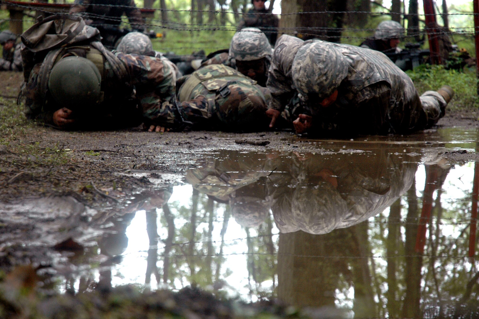 Students in the Air Force Phoenix Warrior Training Course 08-5 crawl under barbed wire and through water during training in a combat first aid class on a Fort Dix, N.J., range June 5, 2008.  The course is taught by the U.S. Air Force Expeditionary Center's Expeditionary Operations School and 421st Combat Training Squadron and prepares security forces Airmen for upcoming deployments. Annually, the USAF EC trains more than 23,000 students in expeditionary- and mobility air force-based courses both with in-residence and distance learning.  (U.S. Air Force Photo/Tech. Sgt. Scott T. Sturkol)