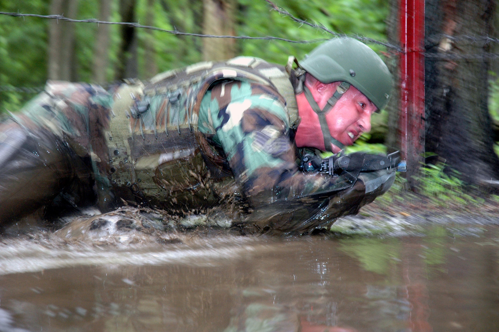 A student in the Air Force Phoenix Warrior Training Course 08-5 crawls under barbed wire and through water during training in a combat first aid class on a Fort Dix, N.J., range June 5, 2008.  The course is taught by the U.S. Air Force Expeditionary Center's Expeditionary Operations School and 421st Combat Training Squadron and prepares security forces Airmen for upcoming deployments. Annually, the USAF EC trains more than 23,000 students in expeditionary- and mobility air force-based courses both with in-residence and distance learning.  (U.S. Air Force Photo/Tech. Sgt. Scott T. Sturkol)