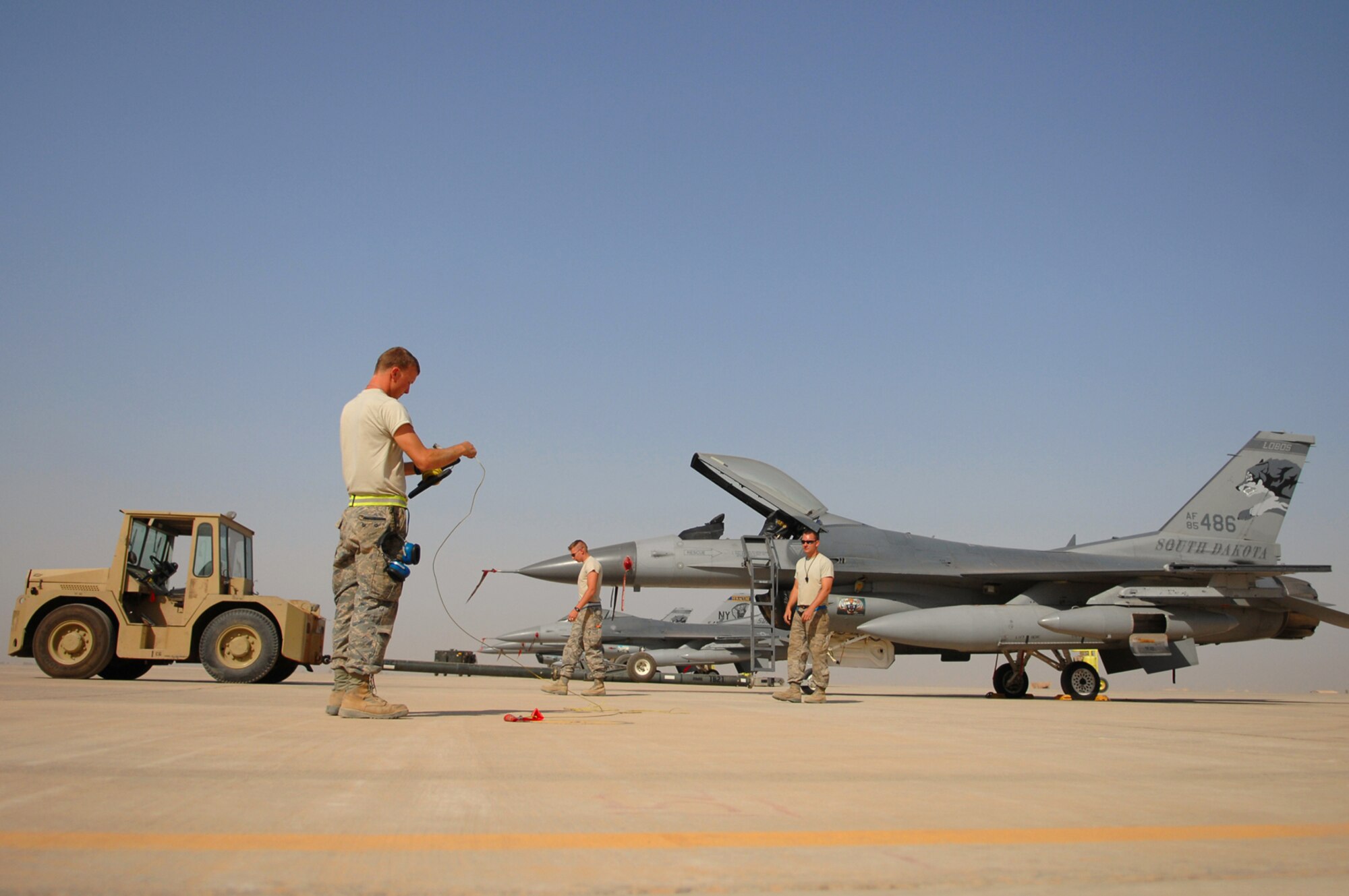 JOINT BASE BALAD, Iraq -- Tech. Sgt. Jake Hermanson, 332nd Expeditionary Aircraft Maintenance Squadron crew chief, unhooks and rolls up a grounding cable attached to an F-16 Fighting Falcon before towing the jet to its appropriate hardened aircraft shelter during a transition between fighter squadrons here, June 13. Aircraft and personnel from the Iowa and Wisconsin Air National Guard will return to the U.S., after being in Iraq for four months; F-16s and Airmen from the South Dakota and New York Air National Guard have arrived here to take their places. Rotating fighters helps reduce the amount of time the aircraft are exposed to the hot and dusty weather of Iraq, which can wreak havoc on the planes' components. Sergeant Hermanson is deployed from the Iowa Air National Guard. (U.S. Air Force photo/ Senior Airman Julianne Showalter)