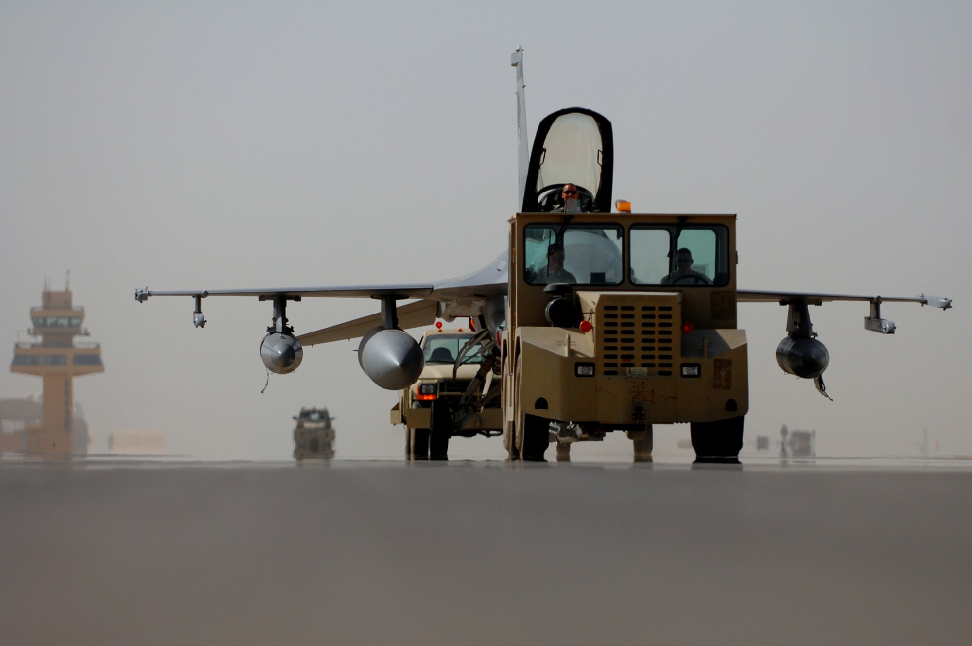 JOINT BASE BALAD, Iraq -- Members of the Iowa and Wisconsin Air National Guard assigned to the 332nd Expeditionary Aircraft Maintenance Squadron, tow an F-16 Fighting Falcon to its appropriate hardened aircraft shelter here, June 13. Aircraft and personnel from the Iowa and Wisconsin Air National Guard will return to the U.S., after being in Iraq for four months; F-16s and Airmen from the South Dakota and New York Air National Guard have arrived here to take their places. Rotating fighters helps reduce the amount of time the aircraft are exposed to the hot and dusty weather of Iraq, which can wreak havoc on the planes' components. (U.S. Air Force photo/ Senior Airman Julianne Showalter)
