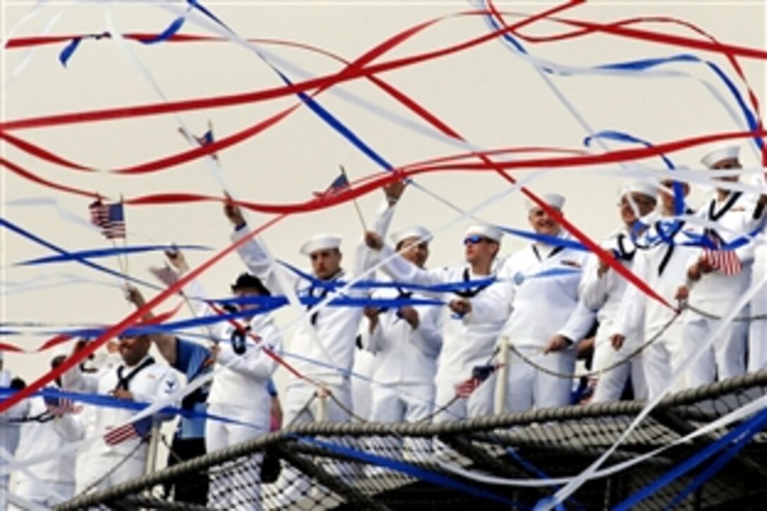 U.S. sailors aboard the aircraft carrier USS Harry S. Truman wave to their friends and family members as red, white and blue streamers shoot through the air after the announcement that the ship is moored, Norfolk, Va., June 4, 2008. 
