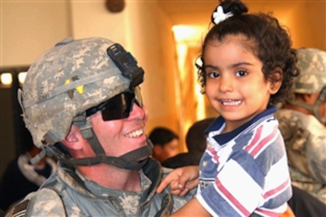 U.S. Army Staff Sgt. Joseph Reinsburrow holds an Iraqi child during a joint U.S. and Iraqi military police mission to distribute toys and school supplies at a girls' school in Hurriyah, Iraq, June 12, 2008. Reinsburrow is assigned to the 64th Military Police Company, Fort Hood, Texas.  
