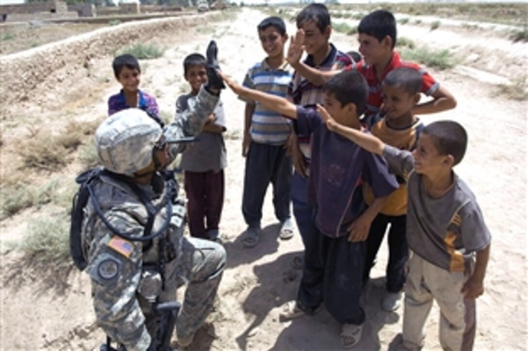 U.S. Army Sgt. Sancho Burlaza high-fives local children while pausing on patrol in support of Operation Sabre Tempest in the village of Madaan, Iraq, June 12, 2008. Burlaza is assigned to the 2nd Squadron, 3rd Armored Cavalry Regiment's 2nd Squadron. Operation Sabre Tempest was launched drive insurgents from villages south of Balad Ruz, Iraq, and encourage citizen patrols.