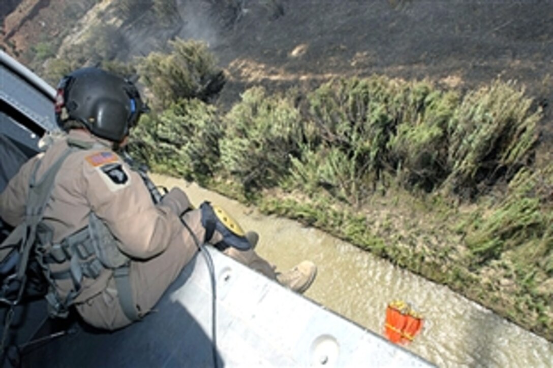 U.S. Army Sgt. Rick D. Peevy, guides his UH-60 Blackhawk in order to fill a bucket with river water to fight wildfires at Fort Carson, Col., June 12, 2008. Peevy is a crew chief assigned to the Colorado Army National Guard's 2nd Battalion, 135th Aviation Regiment. His helicopter crew dropped about 22,000 gallons of water in one day to help fight the fires burning 30,000 acres.
