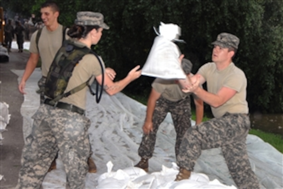U.S. Army Spc. Bethany Scott throws a sandbag to Spc. Robert Alexander to help stop water from rising above a levee in New Harmony, Ind., June 13, 2008. The soldiers are assigned to the Indiana National Guard’s 38th Military Police Company. 