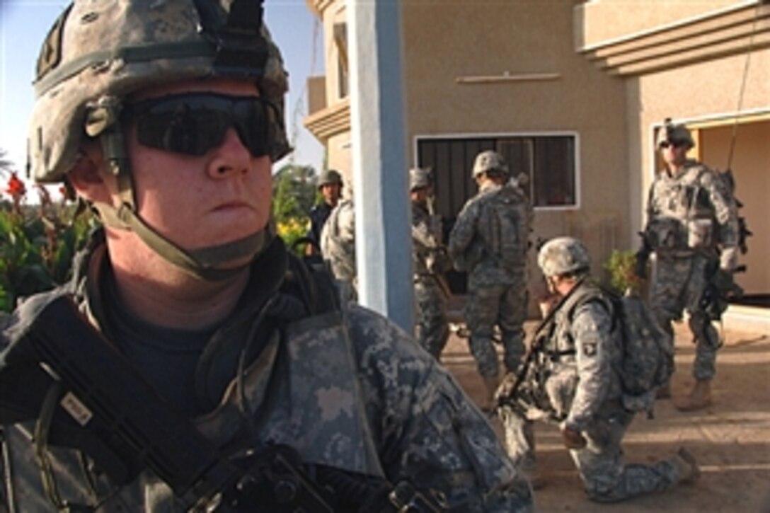 A U.S. soldier scans a road and field for enemies while U.S. and Iraqi soldiers search a building in Ludifiyah, Iraq, June 14, 2008. The U.S. soldiers are assigned to the 101st Airborne Division's 320th Field Artillery Regiment.