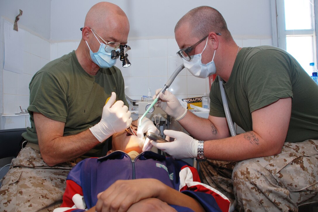 Navy Capt. Edward Kassab (left), dentist and Mount Joy, Pa. resident, and  Seaman Cody Banks, hospital corpsman and Gloucester City, N.J., resident, extract a badly decayed tooth from a young Moroccan boy during a humanitarian civic action visit to the village of Taghjijt June 17. Kassab and Banks are both members of 14th Dental Company, 4th Dental Battalion, 4th Marine Logistics Group and have been attached to a medical detachment of the Utah Air National Guard to conduct medical and dental care in Guelmim Province of Morocco for exercise African Lion 08.