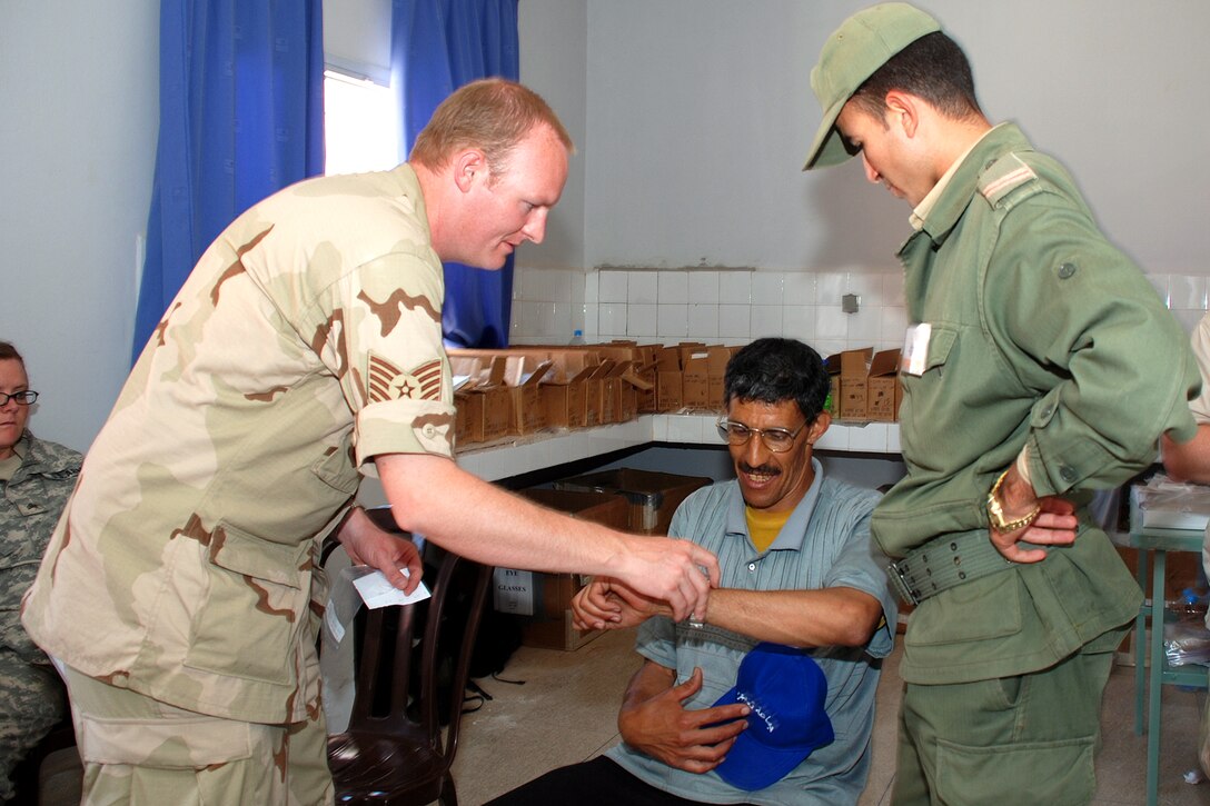 Tech. Sgt. Micah Myers (left), a medic with the 151st medical Group of the Utah Air National Guard and Salt Lake City resident, helps a local Moroccan man test out his new prescription glasses during a humanitarian civic action project to provide free medical and dental care to the residents of Taghjijt, Morocco June 17. The American service members assigned to the HCA task force worked hand-in-hand with their Moroccan medical counterparts during the six-day project that in addition to providing care for in more than 9,000 patient encounters, distributed more than 4,000 pairs of prescription glass throughout the Guelmim Province of Morocco.
