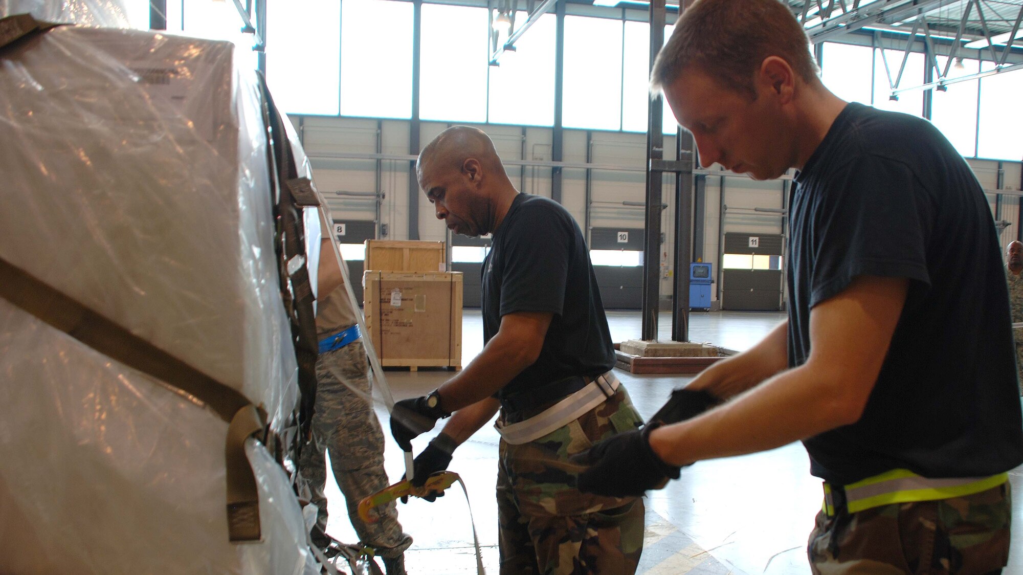 RAMSTEIN AIR BASE, Germany -- (Left to right) Tech. Sgt. John Davis, 69th Aerial Port Squadron transportation journeyman, and Staff Sgt. Dan Anderson, 27th Aerial Port Squadron, Minneapolis Air Reserve Station, Minn., secure plastic weather protection over cargo pallets here May 27. Sergeant Davis was one of 10 459th Air Refueling Wing members who spent their annual tour here in support of airport operations at U.S. Air Forces in Europe headquarters. (U.S. Air Force photo/Tech. Sgt. Amaani Lyle)