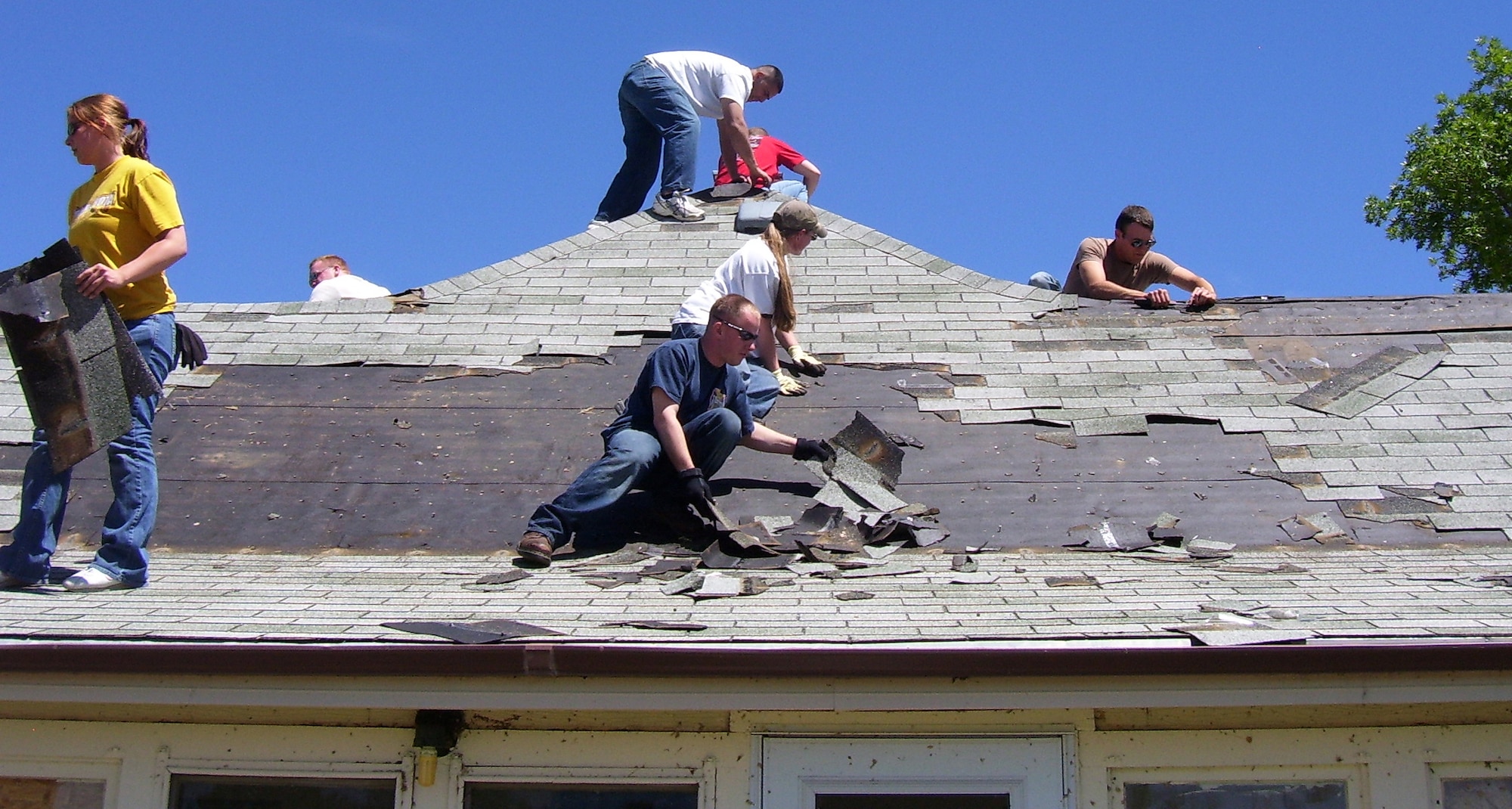 WINDSOR, Colo. -- Airmen from Buckley Air Force Base remove shingles from a home here June 12. More than 30 Airmen removed debris from parks and common areas, tree stumps from yards and delivered furniture to families who lost everything. Buckley also contributed clothing, food, household items and more than $5,000 to the recovery effort. (Courtesy photo)
