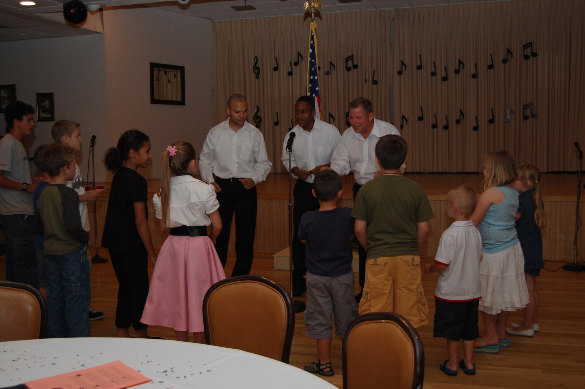 Senior Airman Marcus Jones, 341st Logistics Readiness Squadron, Staff Sgt. Marcus Thomas, 341st Missile Maintenance Squadron, and Chief Master Sgt. Steve Sargent, 341st Space Wing command chief, perform "In the Jungle" for the children present at the American Bandstand-like Tribute, put on by Wing It Theater, Malmstrom's theater group. The tribute was held June 13 and 14 at the Grizzly Bend Club. (U.S. Air Force photo/Airman 1st Class Emerald Ralston)