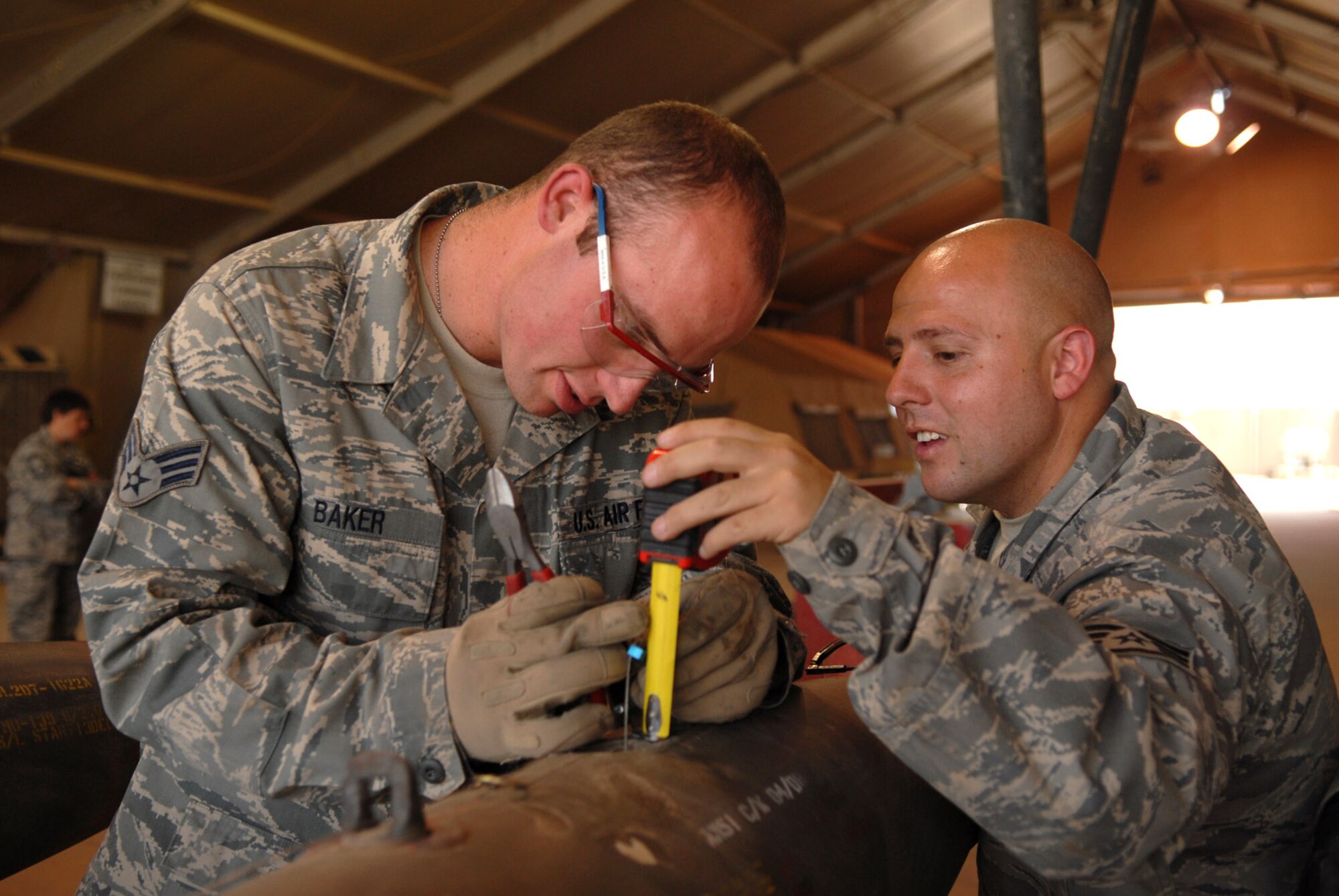 Senior Airman Nathan Baker and Staff Sgt. Jose Landeros measure the length of a guided bomb unit-12 arming lanyard to a bomb body June 16 at Joint Base Balad, Iraq. This measurement varies based on the aircraft to which the munition is attached. The GBU-12 is a laser-guided munition. The Airmen are part of the 332nd Expeditionary Maintenance Squadron munitions systems specialists team responsible for building, maintaining and storing various munitions to support Operation Iraqi Freedom kinetic strikes. Airman Baker is deployed from Hill Air Force Base, Utah; Sergeant Landeros is deployed from Shaw AFB, S.C. (U.S. Air Force photo/Senior Airman Julianne Showalter) 