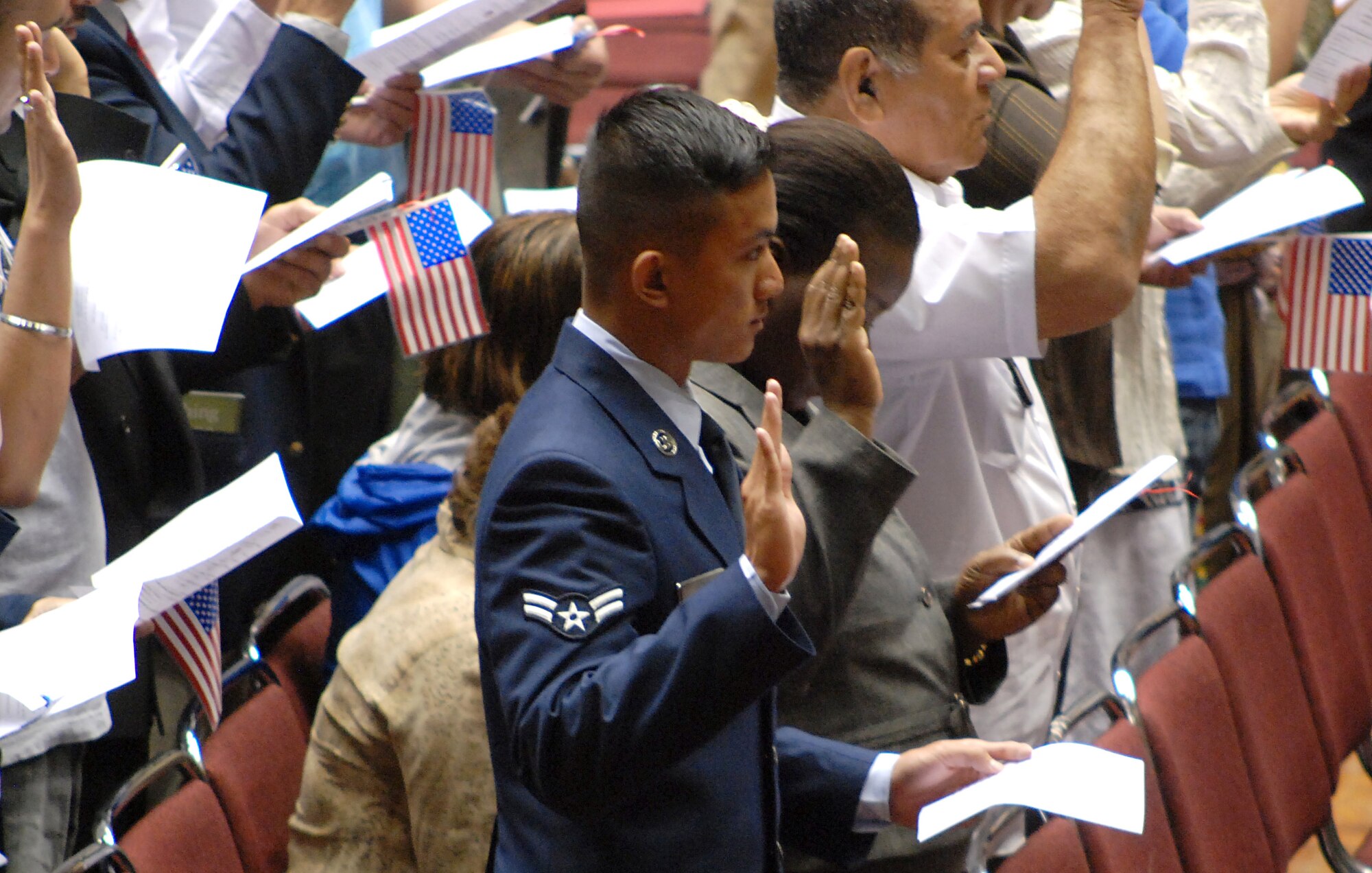 Airman 1st Class Thanh Tran raises his right hand to announce his allegiance to the United States in an oath of citizenship during a naturalization ceremony June 9 at the Municipal Auditorium at Kansas City, Mo.Tran is assigned to the 22nd Air Refueling Wing at McConnell Air Force Base, Kan.  (photo by Airman 1st Class Jessica Lockoski)