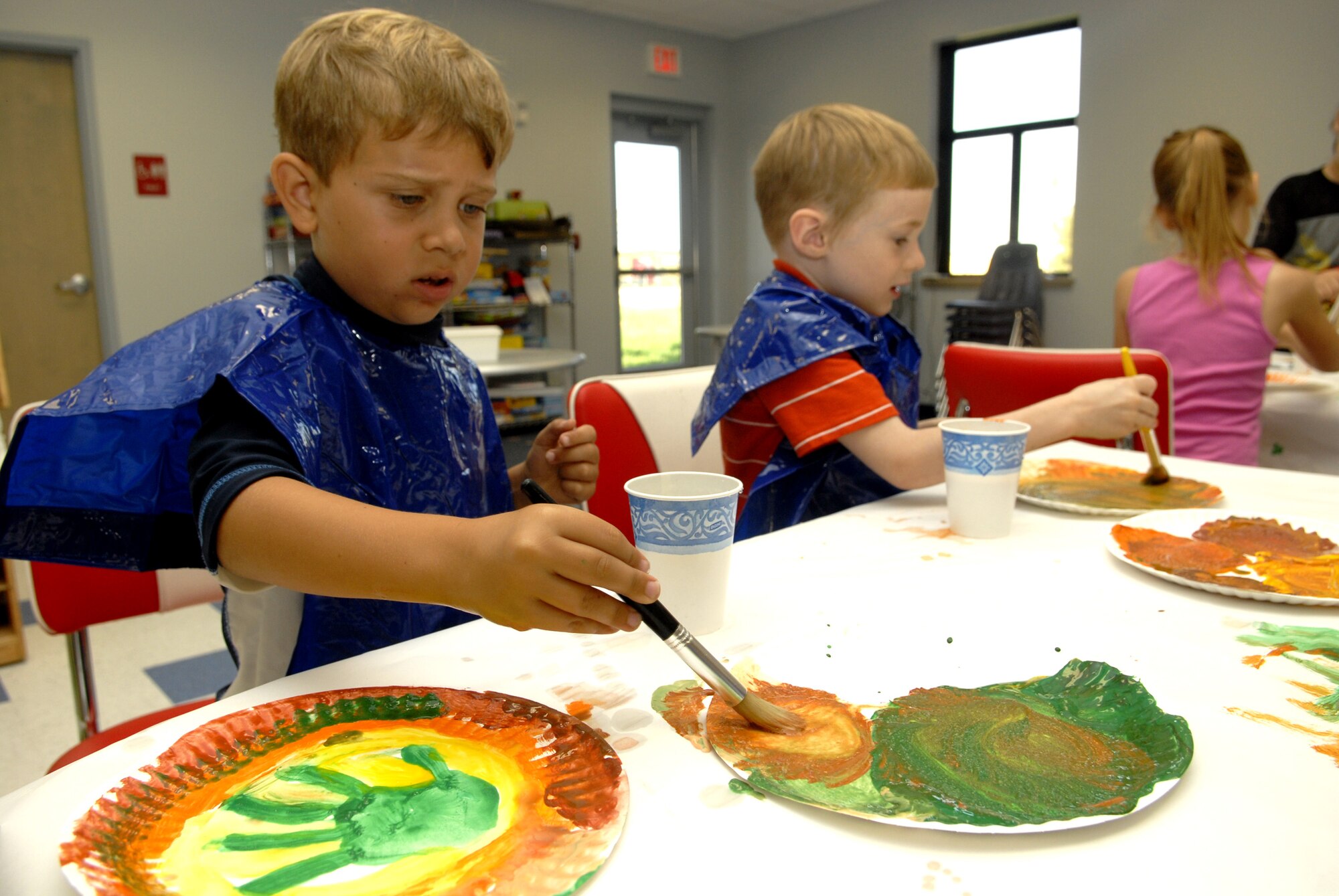 Five-year-olds Andrew Johnson and Logan Sullivan have fun with paints during arts and crafts time at the new School-Age Facility Wednesday. The new 7,250-square-foot, state-of-the-art facility opened May 29th with a ribbon cutting ceremony, just in time for summer vacation. The new facility is located behind the Child Development Center, enabling parents with children of various ages the flexibility of a co-located environment. (U.S. Air Force photo by Senior Airman Kamaile Chan)