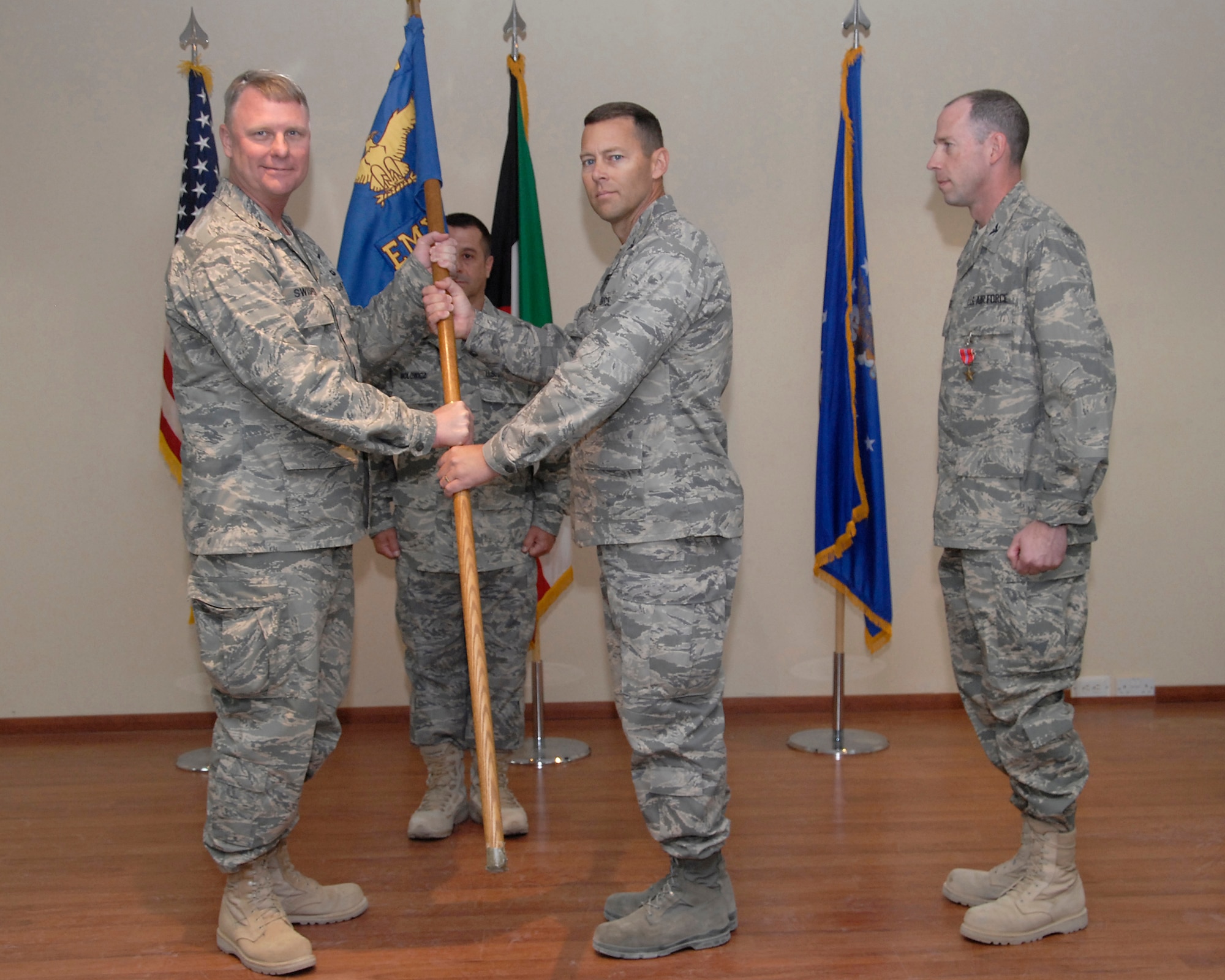 SOUTHWEST ASIA -- Colonel Robert Swisher, 386th Air Expeditionary Wing commander, hands Col. Herbert Phillips the group guidon during the 386th Expeditionary Maintenance Group change of command ceremony here June 15, 2008. Colonel Phillips assumed command from Col. Charles Westgate III. Chief Master Sgt. Raymond Wolowicz, (behind the guidon), 386th EMXG group chief, passed the guidon between the outgoing and incoming commanders. (U.S. Air Force photo/ Staff Sgt. Patrick Dixon)