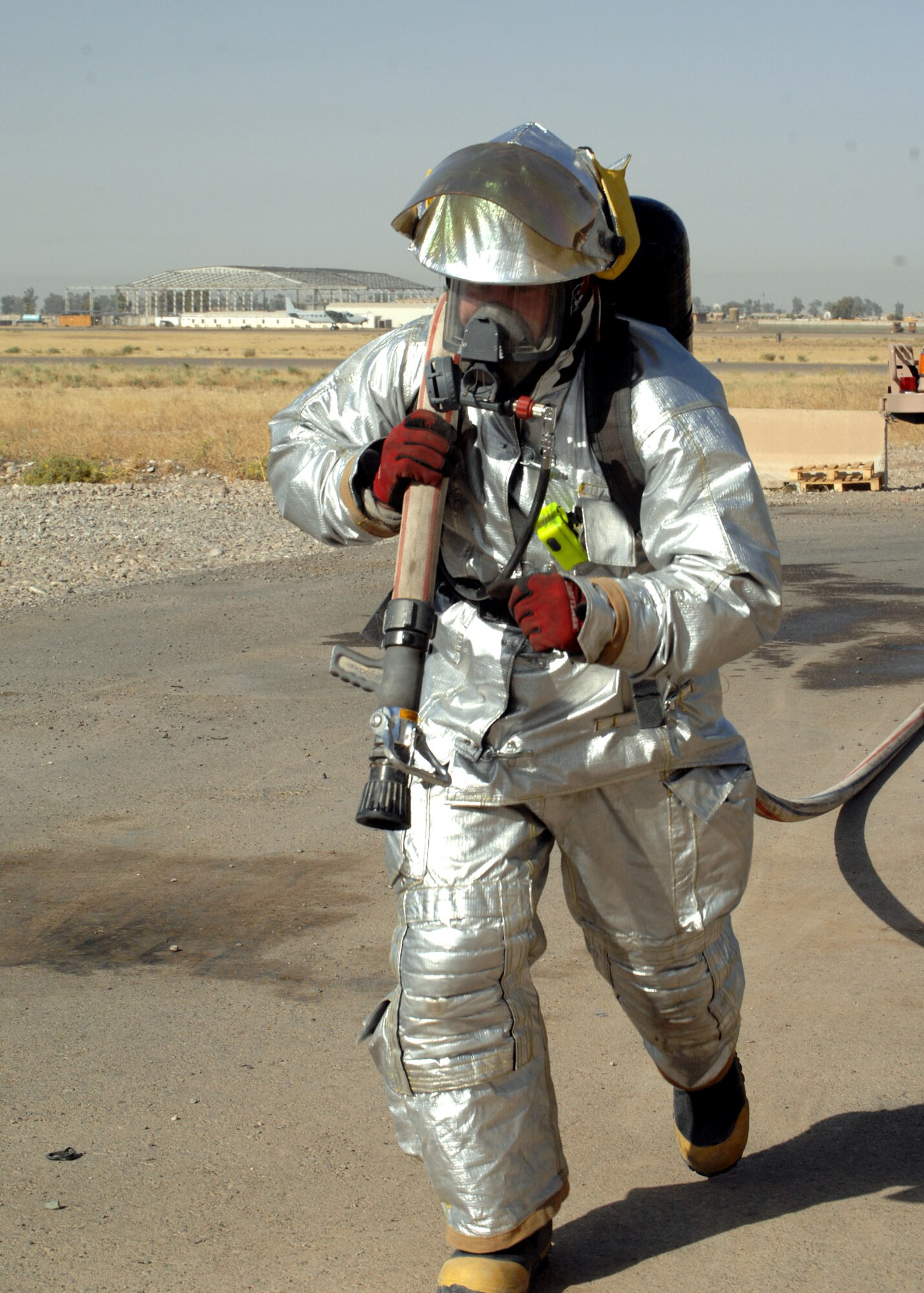 KIRKUK REGIONAL AIR BASE, Iraq – An Airman from the 506th Expeditionary Civil Engineer Squadron Fire and Emergency Services Flight runs with a hose during a training event June 16 here. The event tested the flight's ability to respond to an emergency situation in the deployed setting. (U.S. Air Force photo by Senior Airman SerMae Lampkin) 