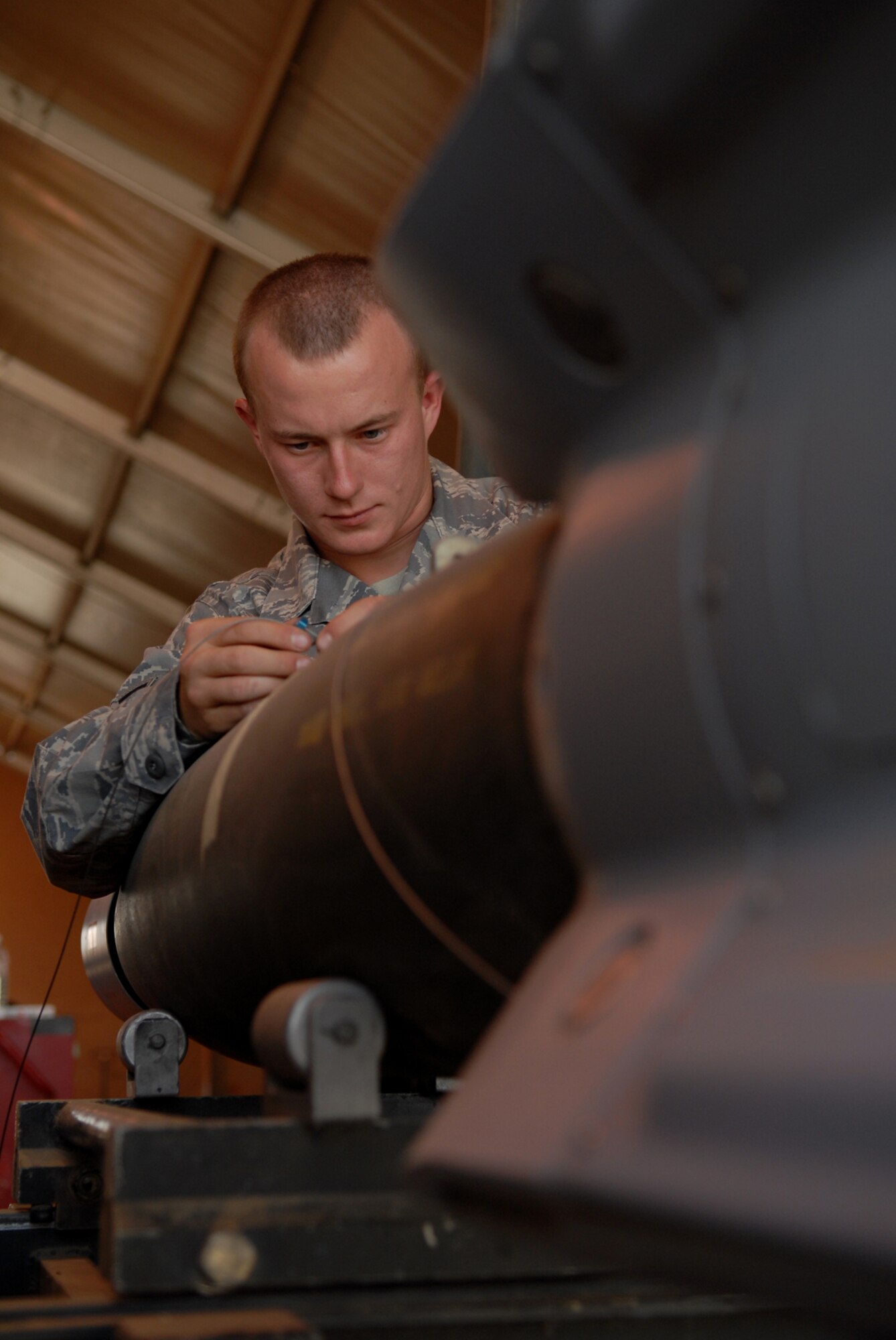JOINT BASE BALAD, Iraq -- Airman 1st Class Richard Spurgeon, 332nd Expeditionary Maintenance Squadron munitions systems specialist, connects a GBU-12 arming lanyard to a bomb body here, June 16. The length of the lanyard is determined based upon on the aircraft it will be attached to. This lanyard controls the initiation timing according to the aircraft specifications; the GBU-12 can self-guide to a target pinpointed by a laser designator, which helps to minimize collateral damage resulting from detonation. Airman Spurgeon is deployed from Shaw Air Force Base, S.C. (U.S. Air Force photo/ Senior Airman Julianne Showalter)