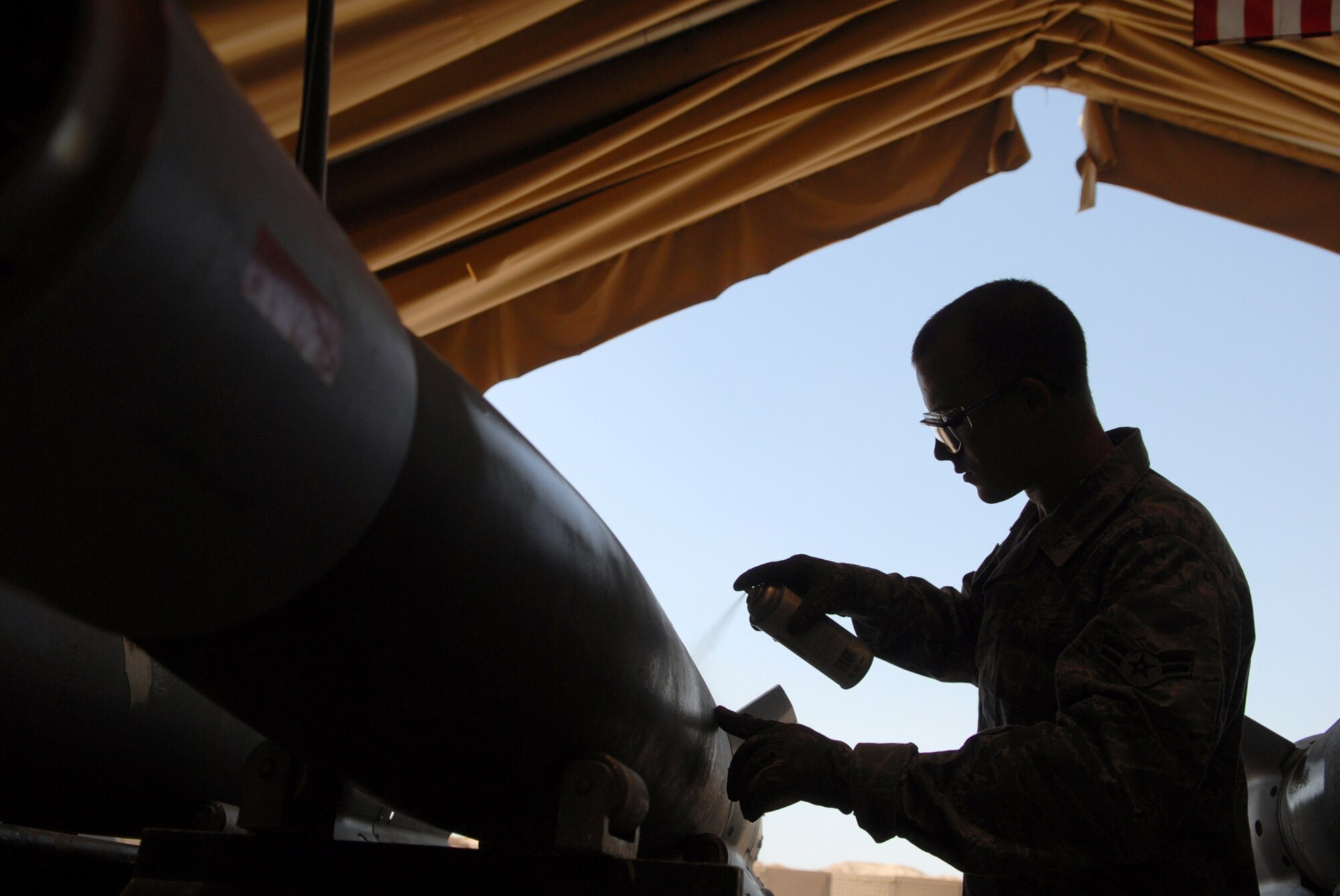 JOINT BASE BALAD, Iraq -- Airman 1st Class Richard Spurgeon, 332nd Expeditionary Maintenance Squadron munitions systems specialist, spray paints munition specifications on a GBU-12 here, June 16. The pained code will tell weapons loaders the munition type and what components are contained in it. The GBU-12 can self-guide to a target pinpointed by a laser designator, which helps to minimize collateral damage resulting from detonation.  Airman Spurgeon is deployed from Shaw Air Force Base, S.C. (U.S. Air Force photo/ Senior Airman Julianne Showalter)
