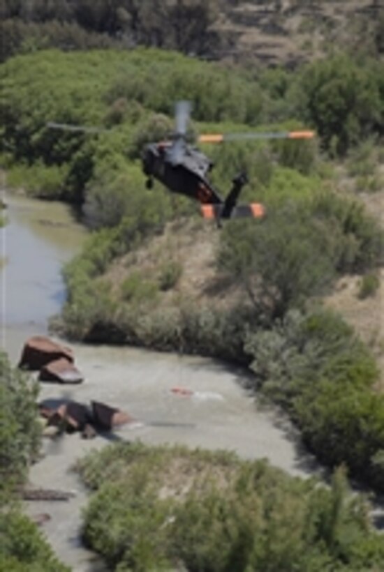 A UH-60 Blackhawk helicopter from Alpha Company, 2nd Battalion, 135th Aviation Regiment, Colorado Army National Guard fills a bucket with river water to fight wildfires at Fort Carson, Colo., on June 12, 2008.  Service members from the Colorado Army National Guard have been assisting several other agencies in battling the blazes since June 9.  Wildfires have been burning in the PiÒon Canyon area since June 8.  