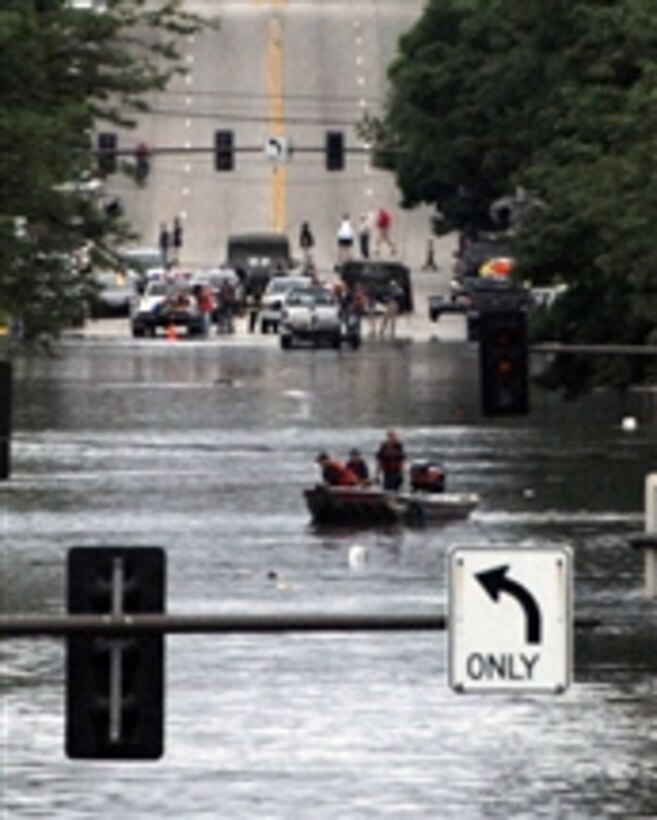 U.S. soldiers assigned to the Iowa Army National Guard assist local police with traffic and crowd control as search and rescue teams patrol flooded streets in search of stranded citizens in Cedar Rapids, Iowa, on June 12, 2008.  Iowa National Guard soldiers and airmen are working with state and local agencies to provide security and help with flood relief operations.  