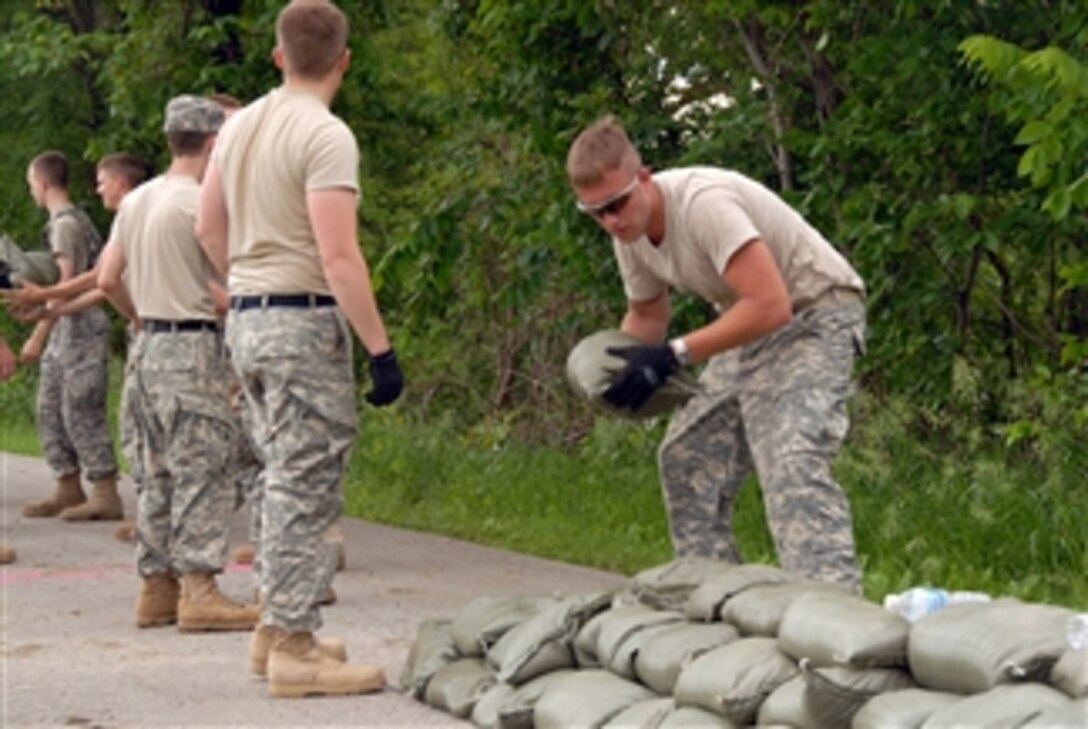 U.S. Army Spc. Kyle Weber (right) from Bravo Company, Brigade Special Troops Battalion, Military Intelligence places sandbags on the levee in Des Moines, Iowa, as the other members of his unit pass them up the line on June 12, 2008.  Iowa National Guard soldiers and airmen are working with state and local agencies to provide security and help with flood relief operations.  
